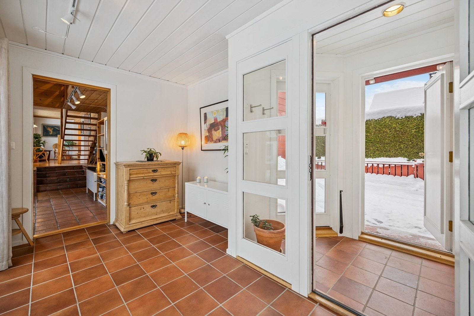 Vindfanget har flislagt gulv med varmekabler og en dør med glass inn til hallen. Galleribilde