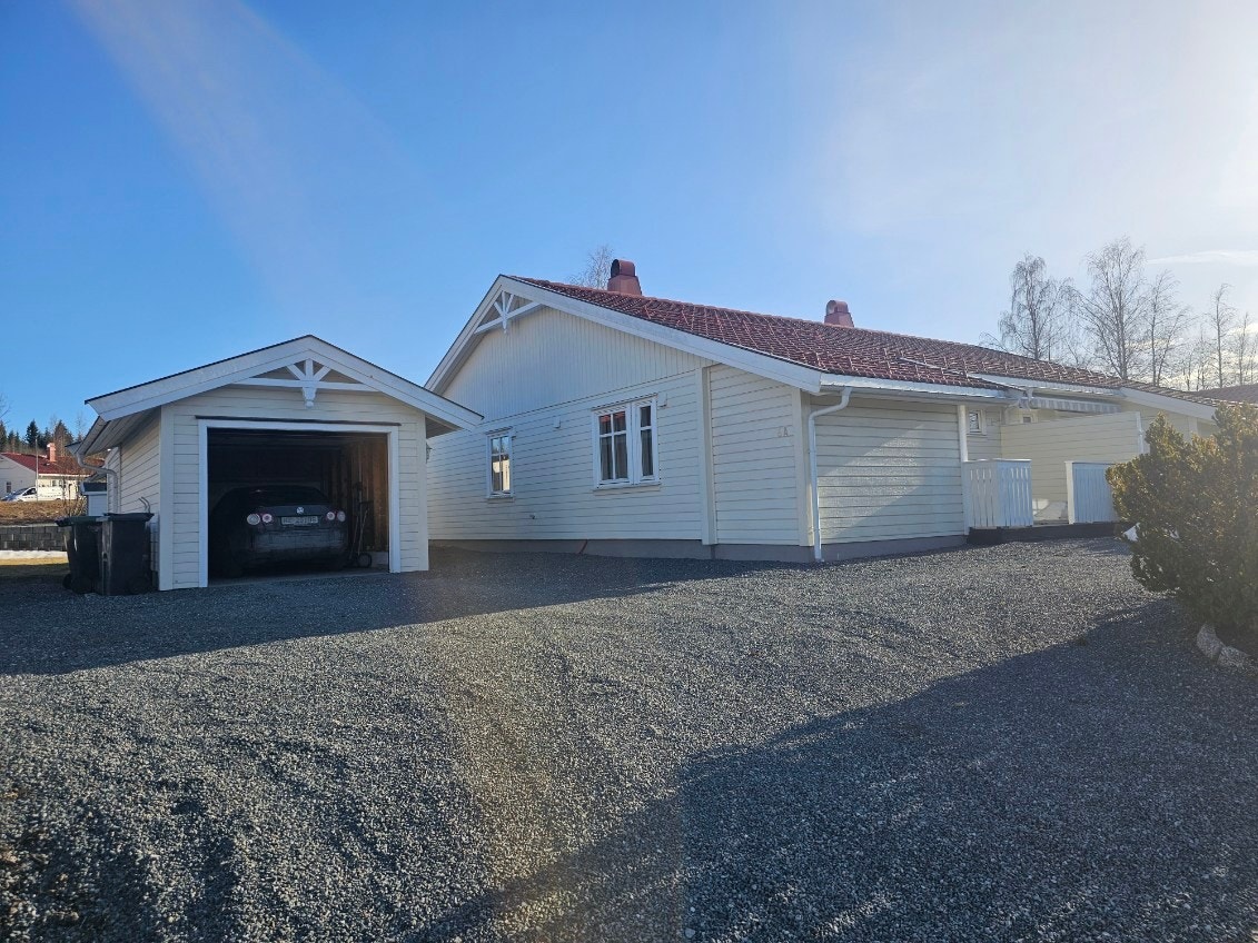 Gruset gårdsplass og hageområde bak garasje og ved terrasse. Galleribilde