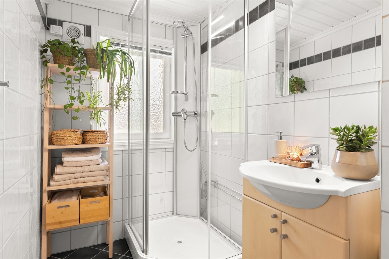 Lyst flislagt bad med dusjkabinett, servant med innredning, toalett og varmekabler i gulv. Galleribilde