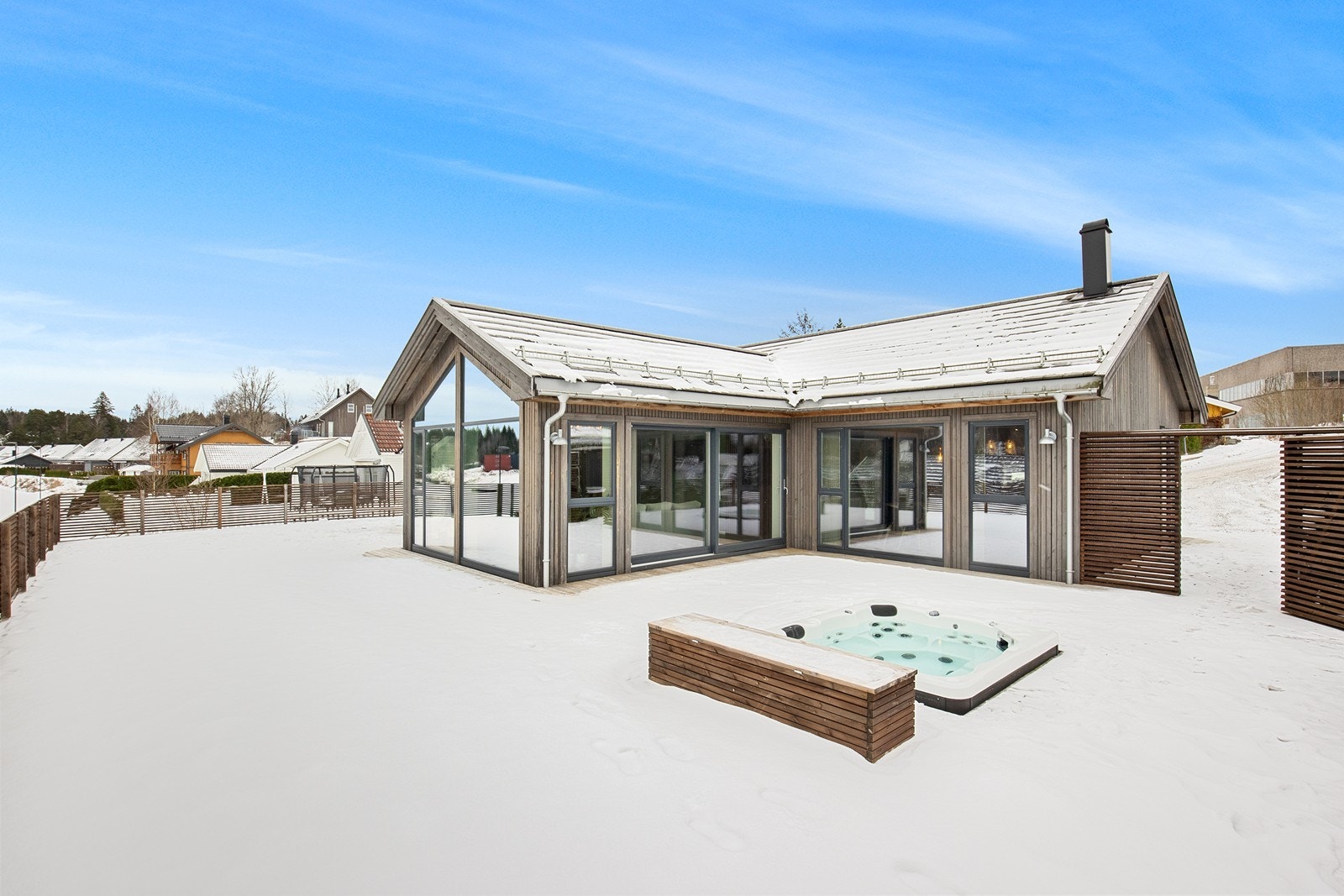 En moderne enebolig med store glassflater som åpner opp mot en romslig terrasse. Galleribilde