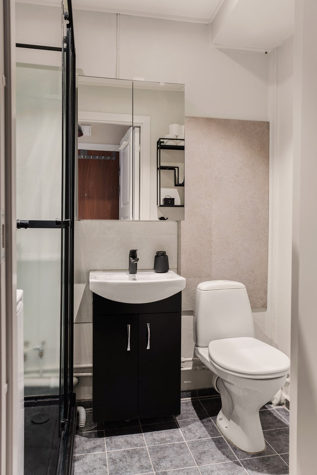 Flislagt bad med toalett, servant med underskap og speilskap. Galleribilde