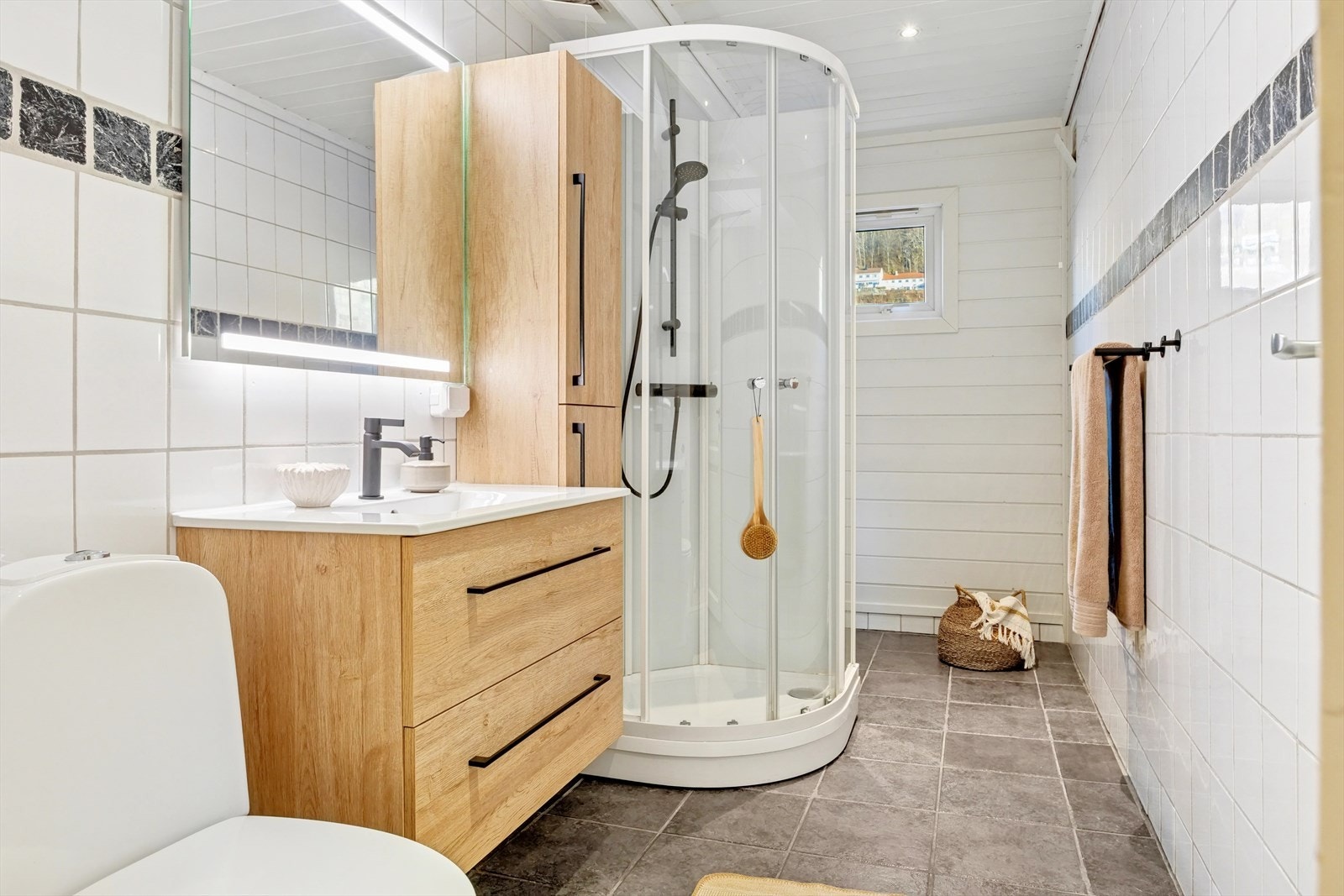 Baderommet er 6,5 kvm med keramiske fliser på gulv, vegger/ malt panel og malt panel med halogen spotlights i himling. Galleribilde