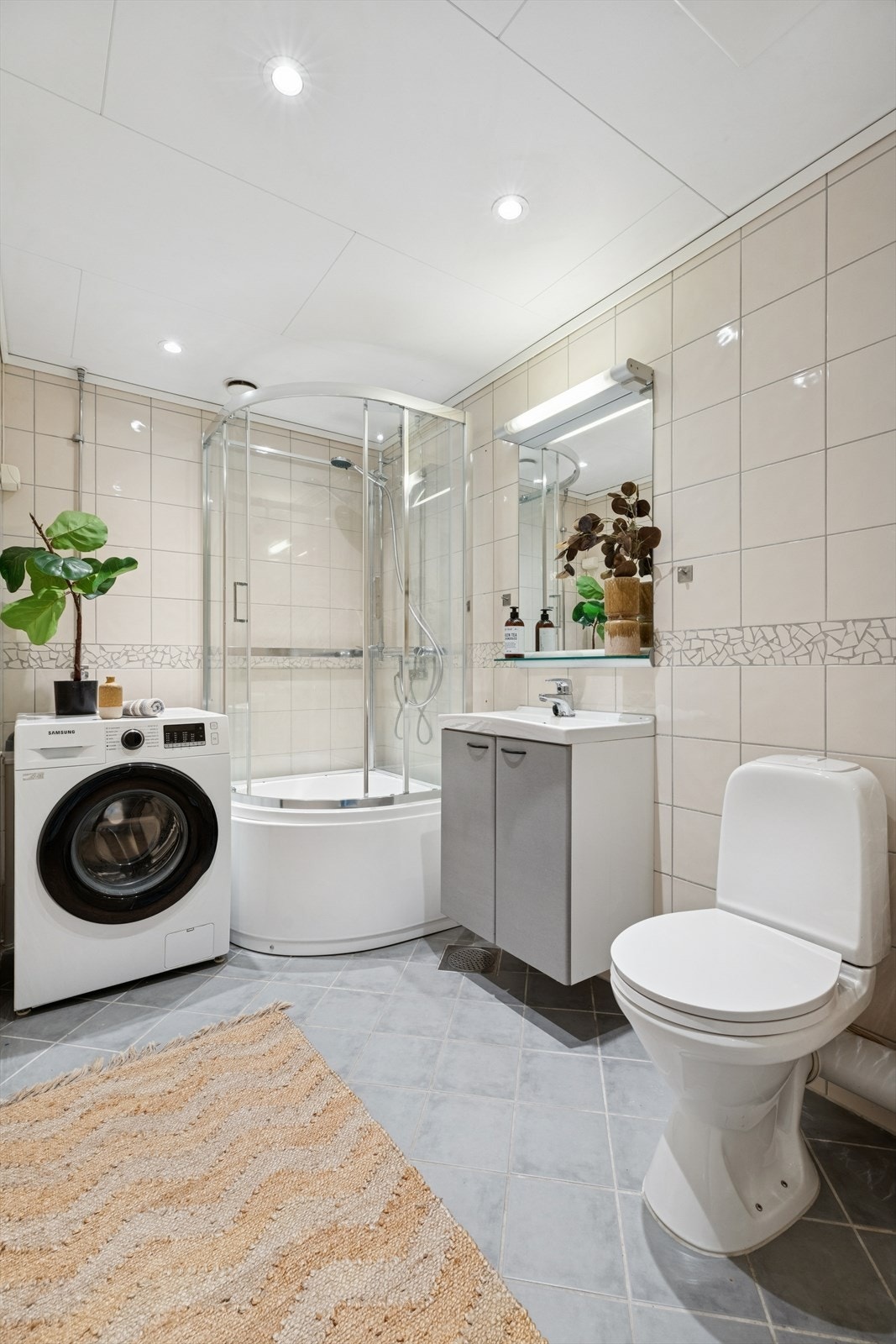 Pent baderom med downlights og flislagte gulv- og veggflater som ble rehabilitert i regi av borettslaget Galleribilde