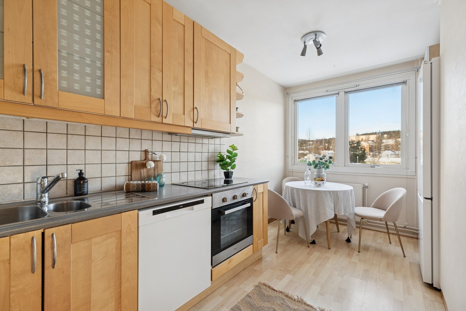 Kjøkkeninnredningen har profilerte skapfronter i over- og underskap med noe glassfelt i overskap, laminat benkeplate med dobbel oppvaskkum og benkebeslag Galleribilde