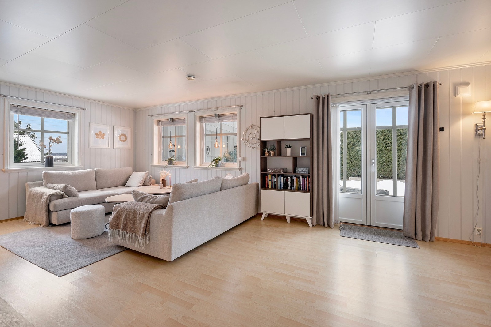 Lyst malt panel, lys laminat og store vindusflater går igjen i boligen og sørger for et gjennomgående, lyst uttrykk med rikelig naturlig lys Galleribilde