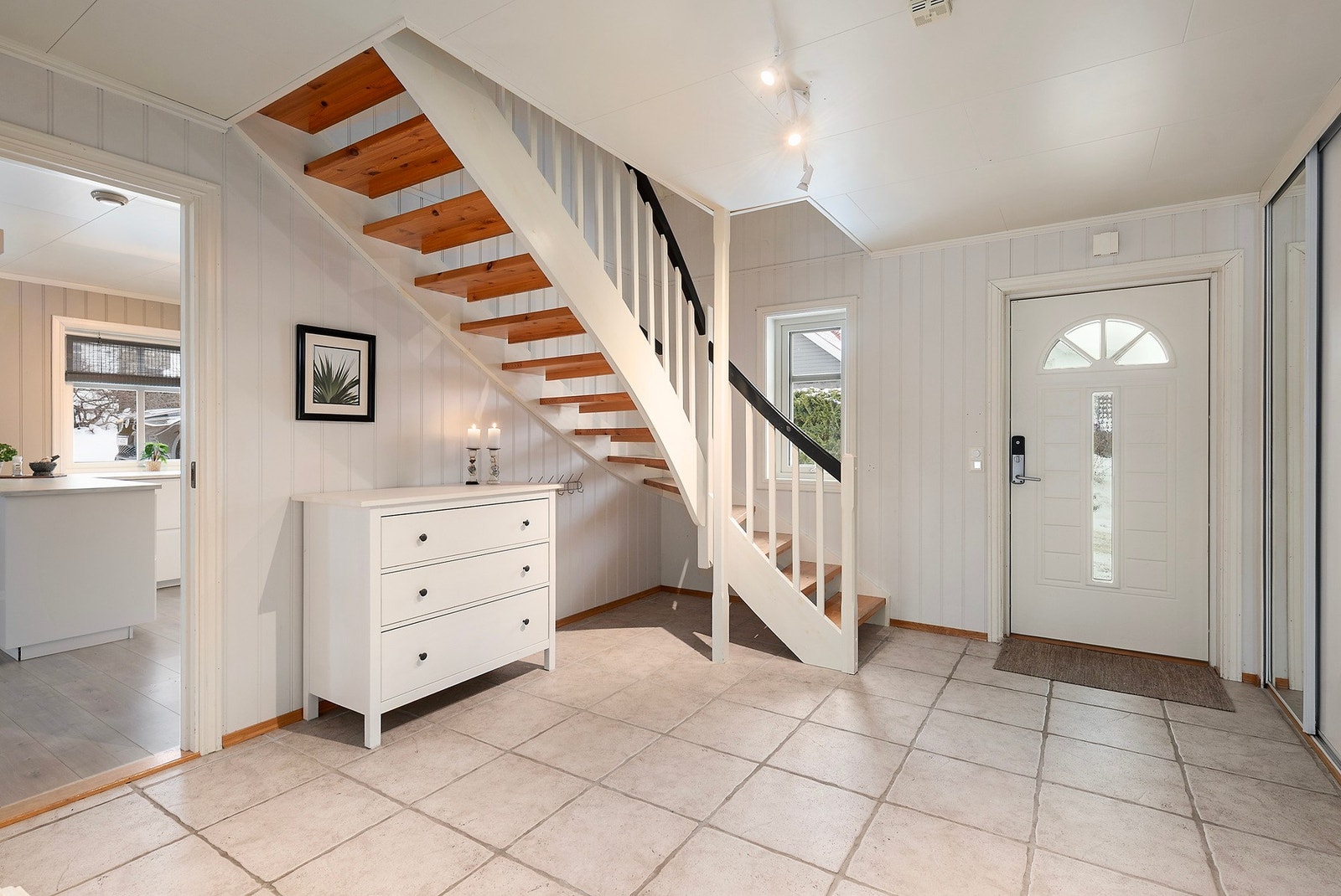 Her kommer du inn i lys entré med flislagt gulv med varmekabler og romslig skyvedørsgarderobe Galleribilde