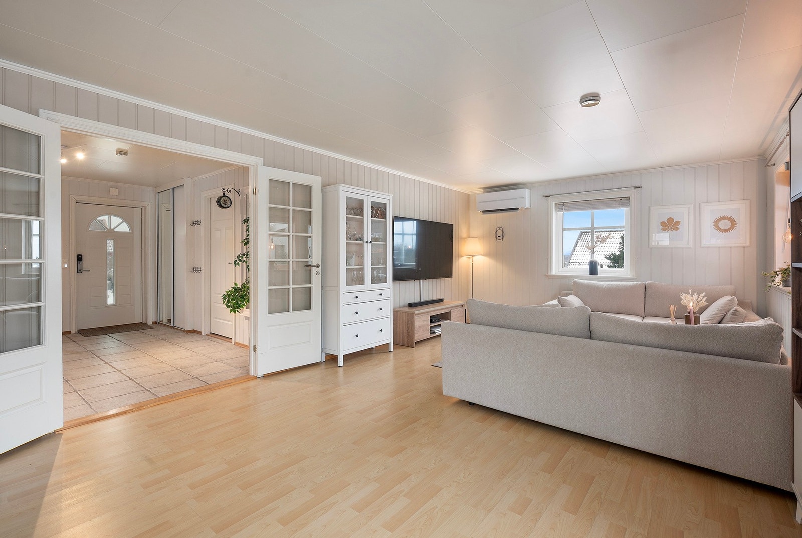 Fra entreen er det adkomst til både stue og kjøkken - Lyst gulv og malt panel i begge rom gir en god flyt mellom rommene Galleribilde