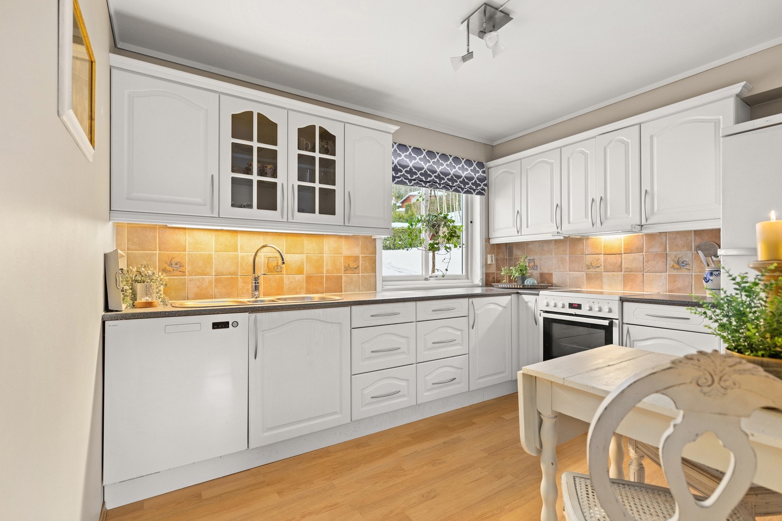 Separat kjøkken i lyse farger, fliser mellom over og underskap. Galleribilde