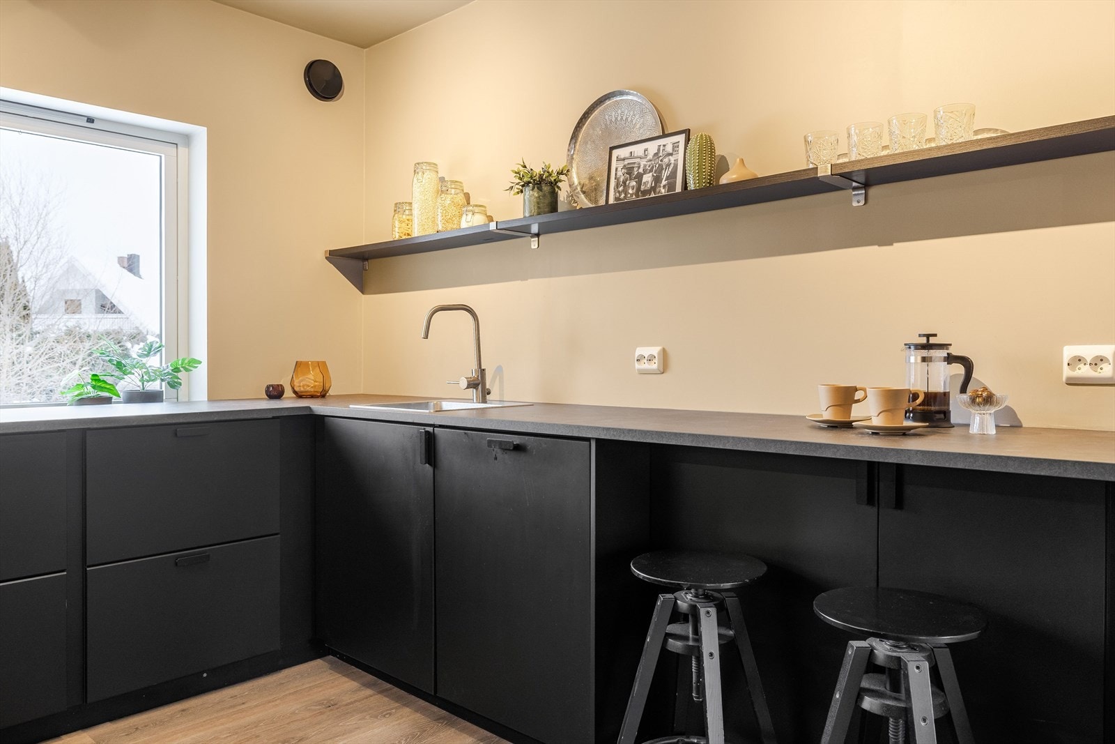 Innredning med svarte, glatte fronter og benkeplate i laminat med nedfelt oppvaskkum i rustfritt stål. Galleribilde