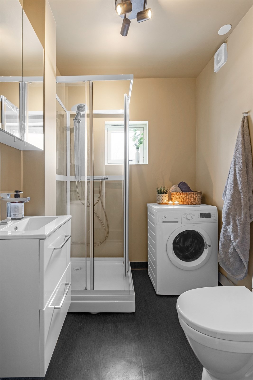 Bad med belegg på gulvet med varmekabler og våtromstapet på veggene. Det er utstyrt med gulvmontert toalett og har opplegg for vaskemaskin. Galleribilde