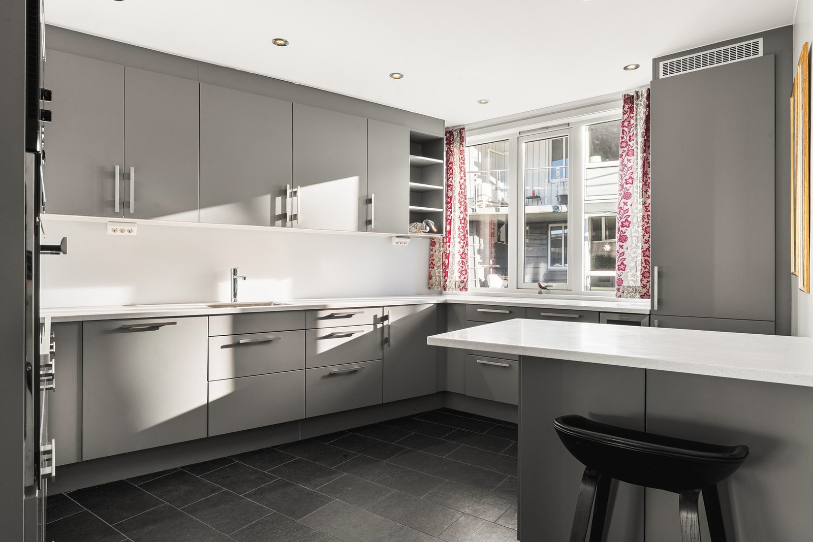 Kjøkkenet på 12,8 kvm har skifer fliser på gulv og kjøkken levert av HTH med slette fronter og corian benkeplate. Galleribilde