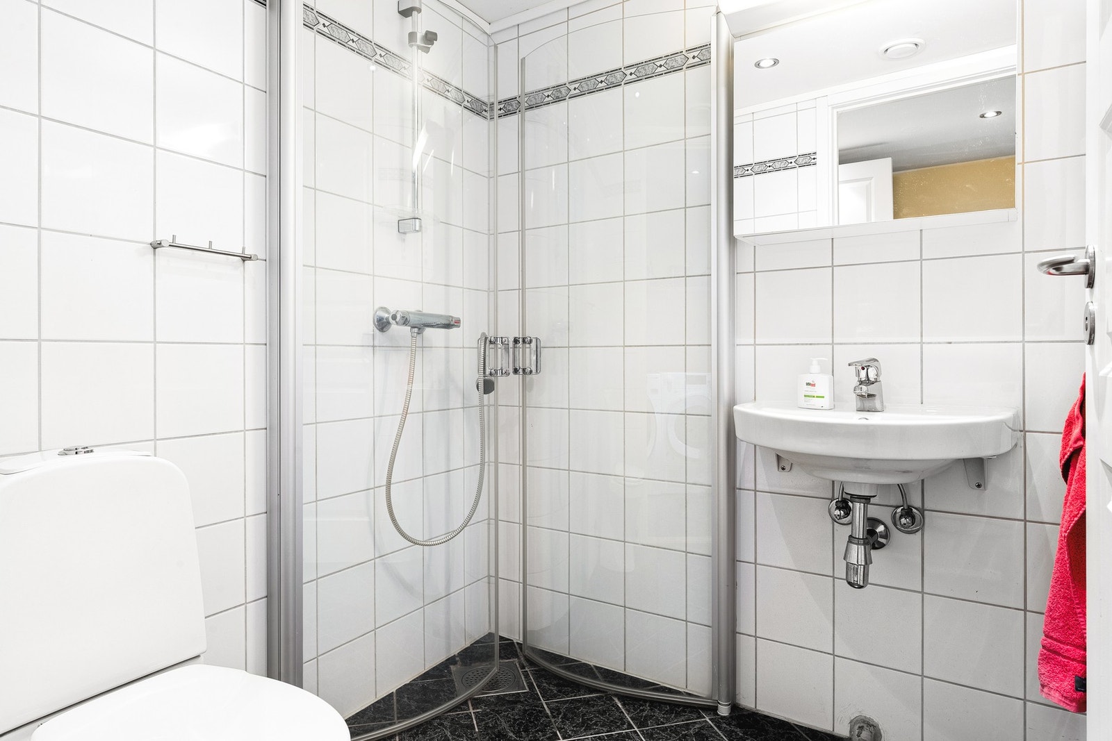 Helfliset bad med dusj, toalett og servant. Badet har varmekabler i gulv. Galleribilde