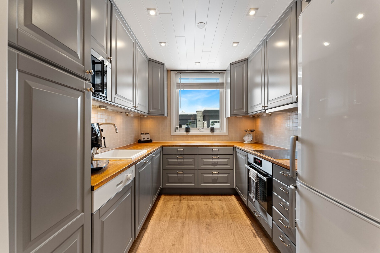 Kjøkken fra IKEA (2018) med profilerte fronter og heltre benkeplate. Av integrerte hvitevarer medfølger platetopp, stekeovn og oppvaskmaskin. Det er avsatt plass til kjøl/frys. Galleribilde