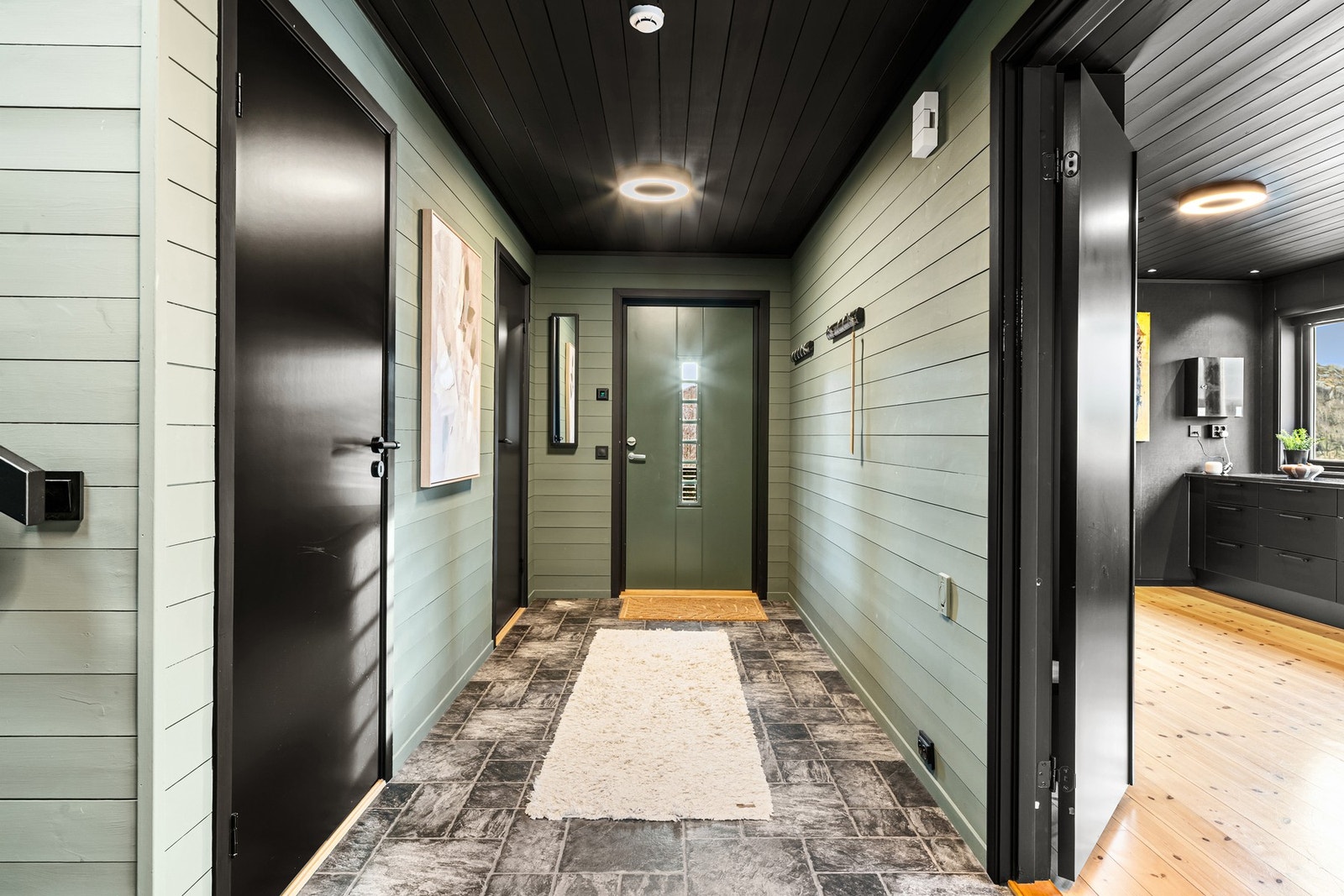 Men kommer inn til boligens hovedetasje til en romslig entré. Entreen har plass til oppheng av yttertøy og sko. En funksjonell entré som knytter rommene i hovedetasjen sammen. Galleribilde