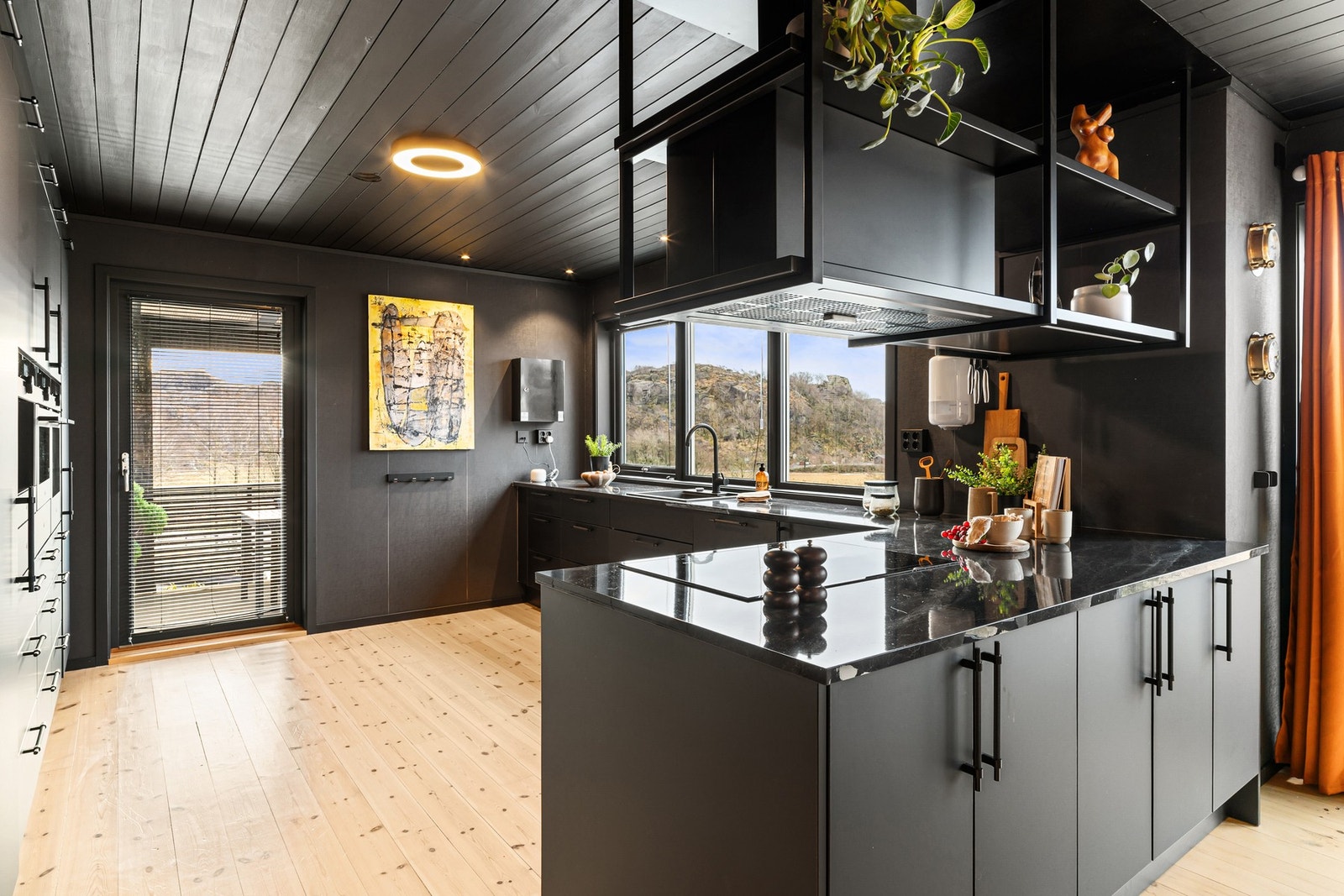 Kjøkkenet har slette sorte fronter og mørk laminert benkeplate Galleribilde