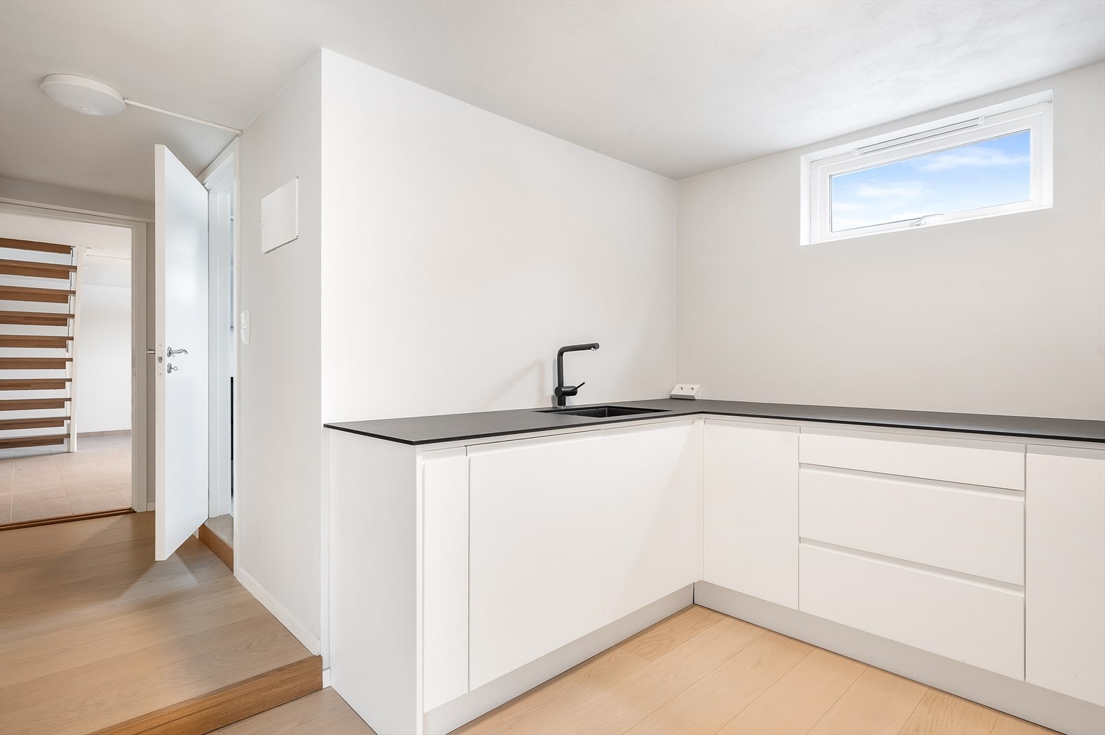 Kjøkkenet har hvite glatte fronter og rikelig med benkeplass Galleribilde