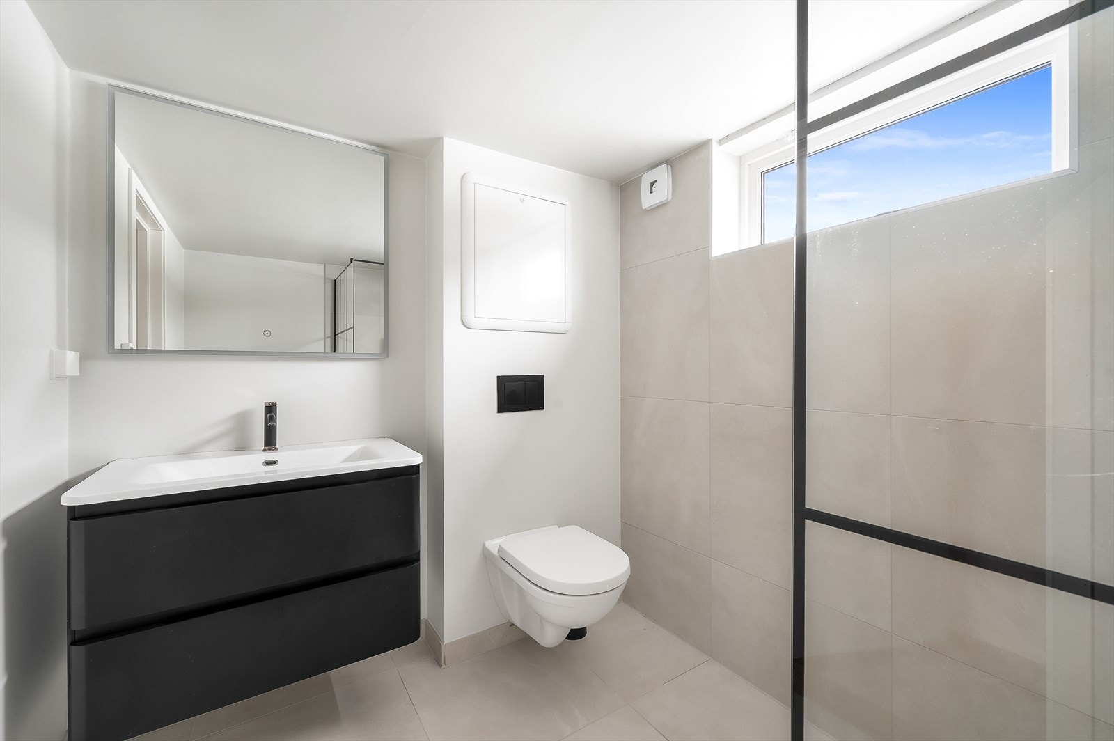 Rommet har en stilren innredning med oppbevaring i skuffer og lysspeil over servant Galleribilde