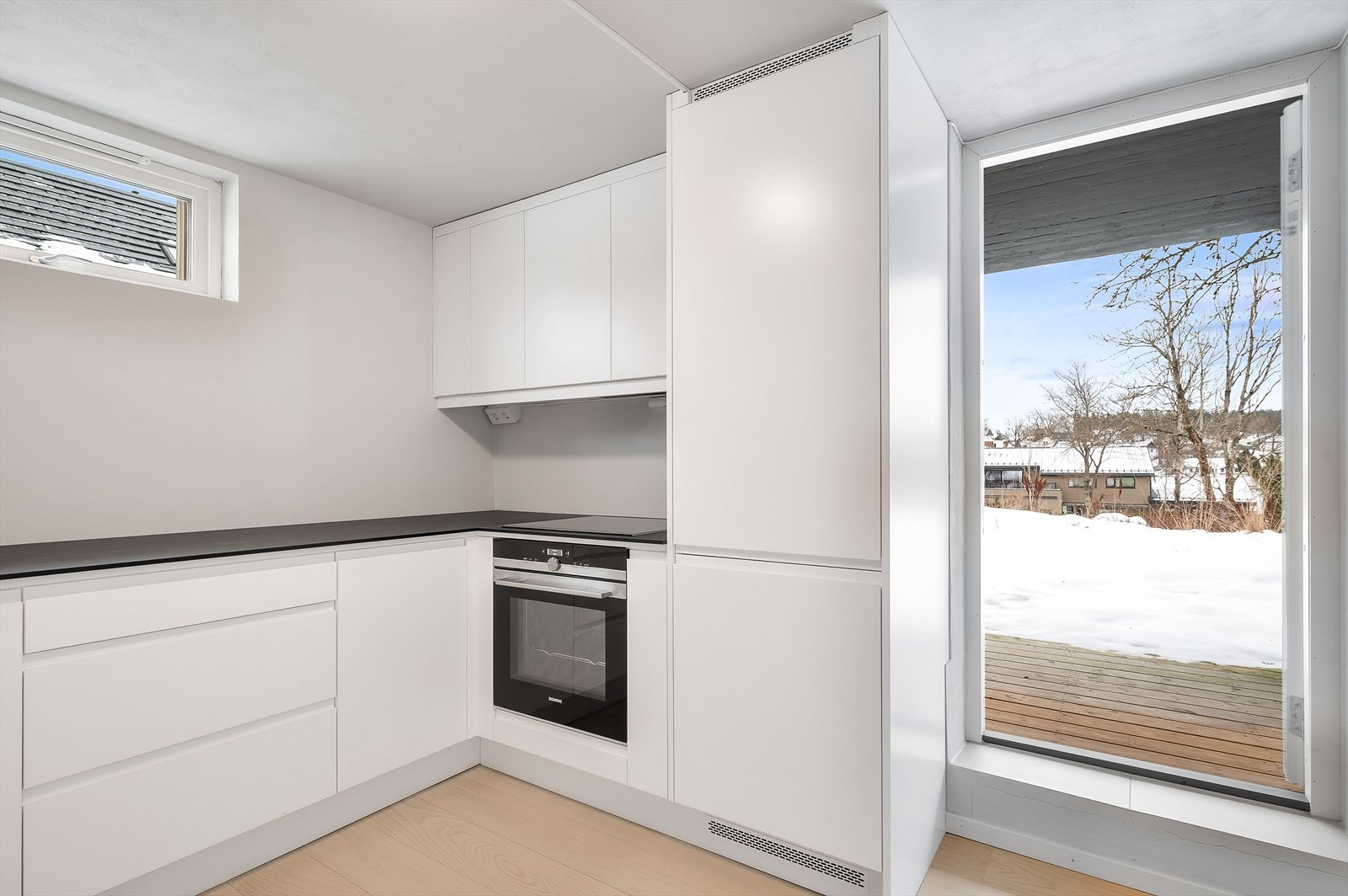 Kjøkkenet har integrerte hvitevarer som inkluderer oppvaskmaskin, ovn, platetopp og kjøl-og fryseskap Galleribilde