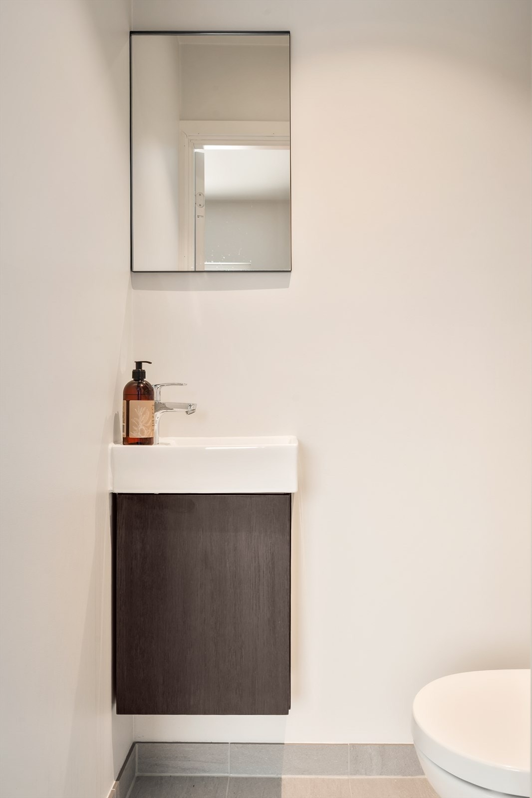 Fra entréen er det adkomst til wc med servant, speilskap og vegghengt toalett Galleribilde