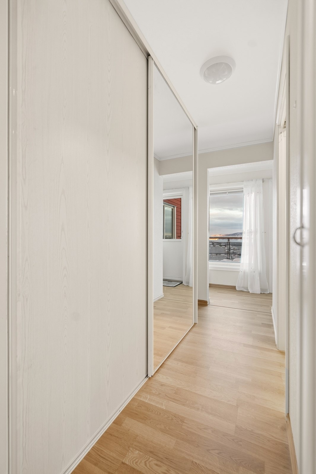 Gang mellom gang og kjøkken/stue inneholder en stor skyvedørsgarderobe. Galleribilde