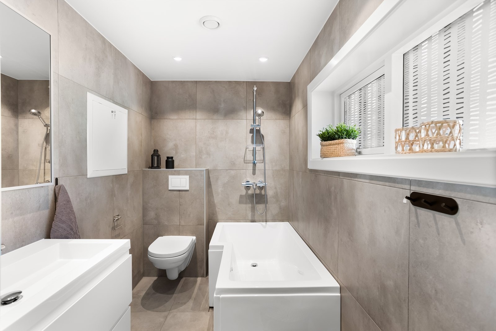 Badet er innredet med servant med underskap, speil, vegghengt toalett og badekar. Galleribilde