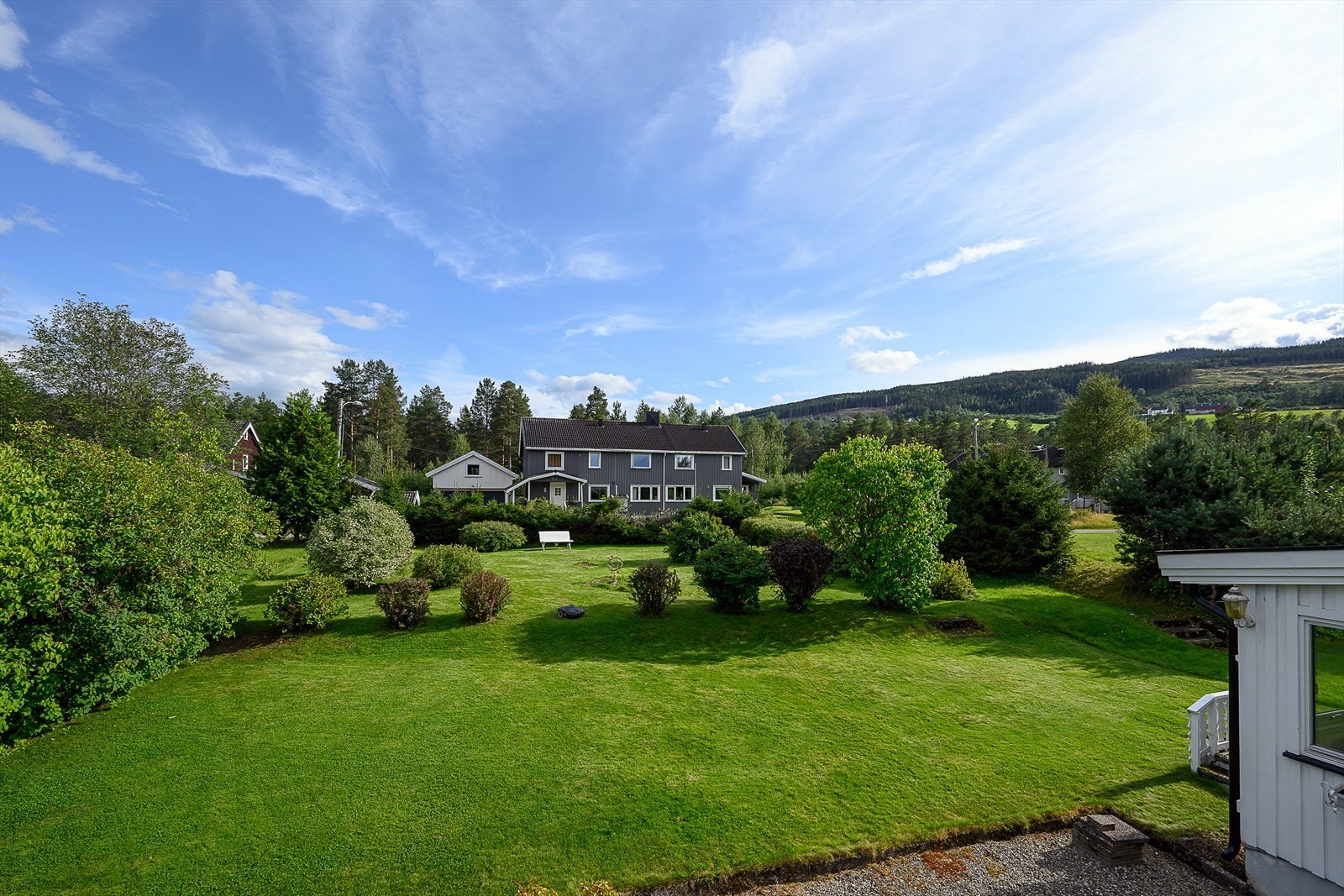 Sommerbilde over uteområde som viser felles eiet tomt i sameiet som er opparbeidet med plenareal, beplantning. Galleribilde