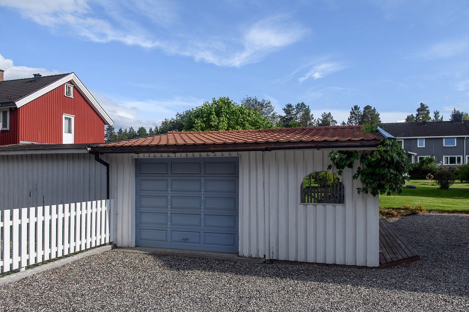 Sommerbilde av garasje med biloppstillingsplass til en bil Galleribilde