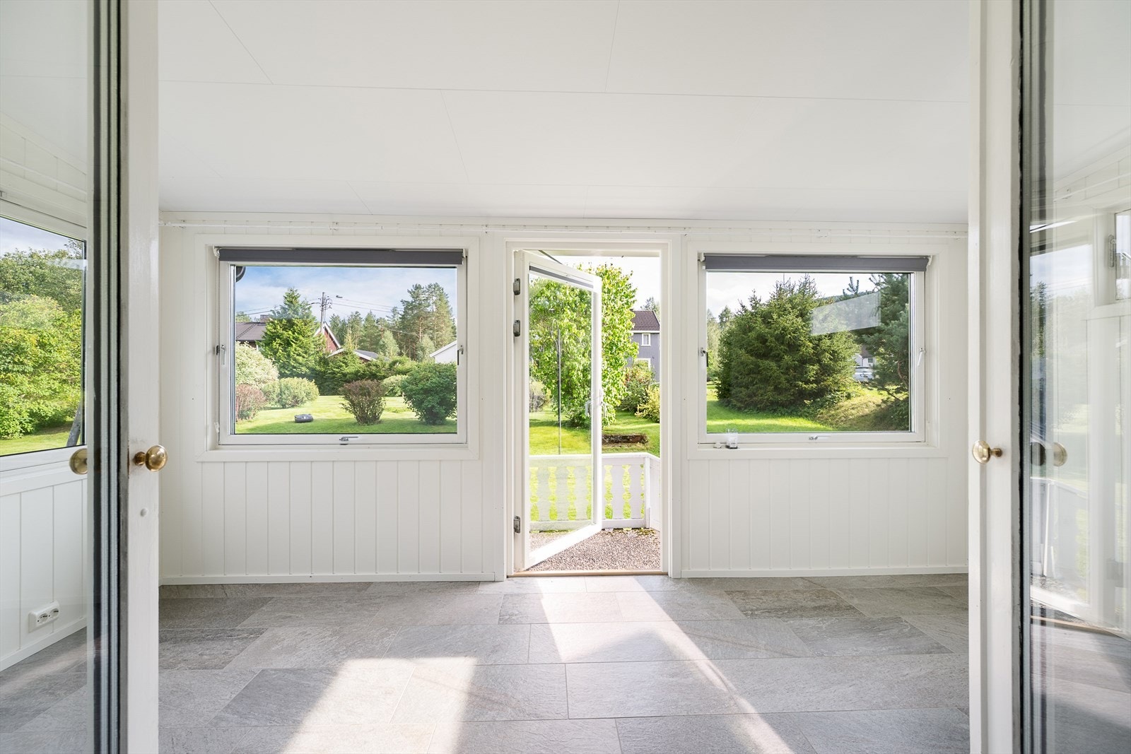 Innbygget terrasse har fliser på gulv, plater på vegger og store vinduer som bidrar med god belysning Galleribilde