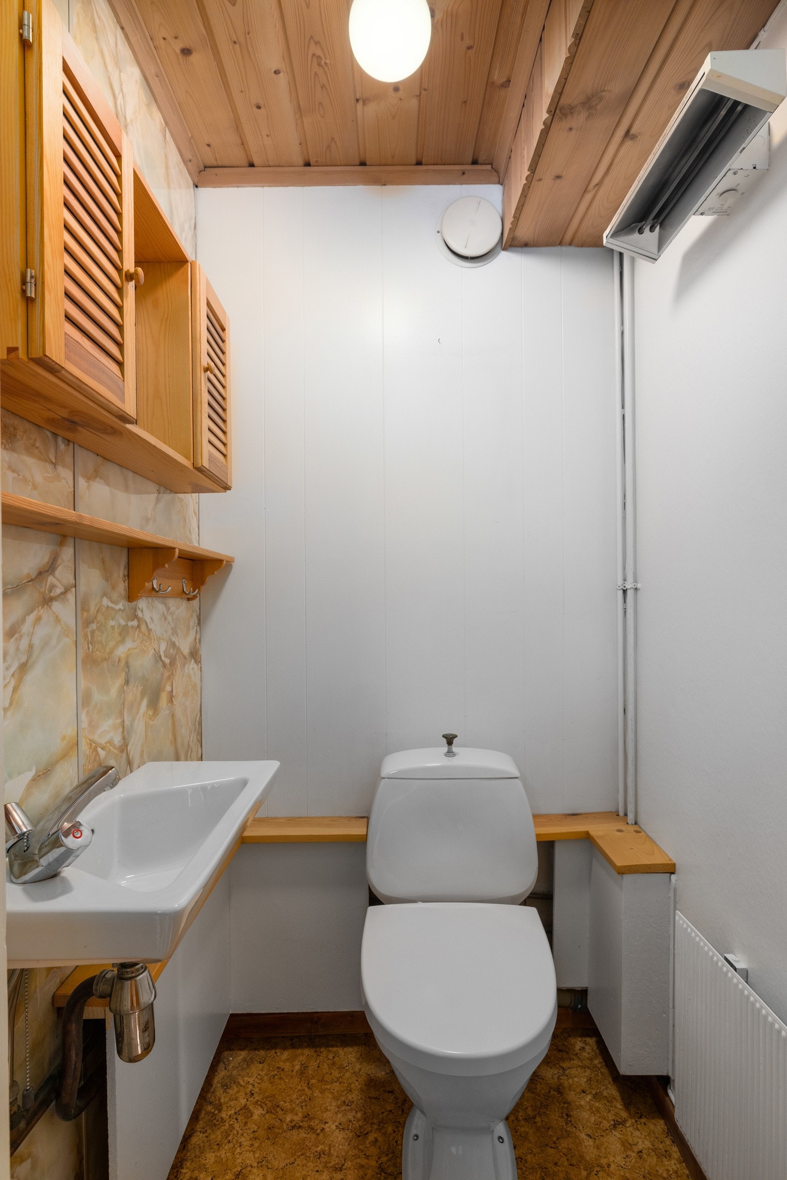 Toalettrommet i underetasjen har belegg på gulv, ulike overflater på vegger og panel i himling. Rommet er utstyrt med servant og gulvmontert toalett. Oppvarming med stråleovn og radiator. Naturlig avtrekk Galleribilde
