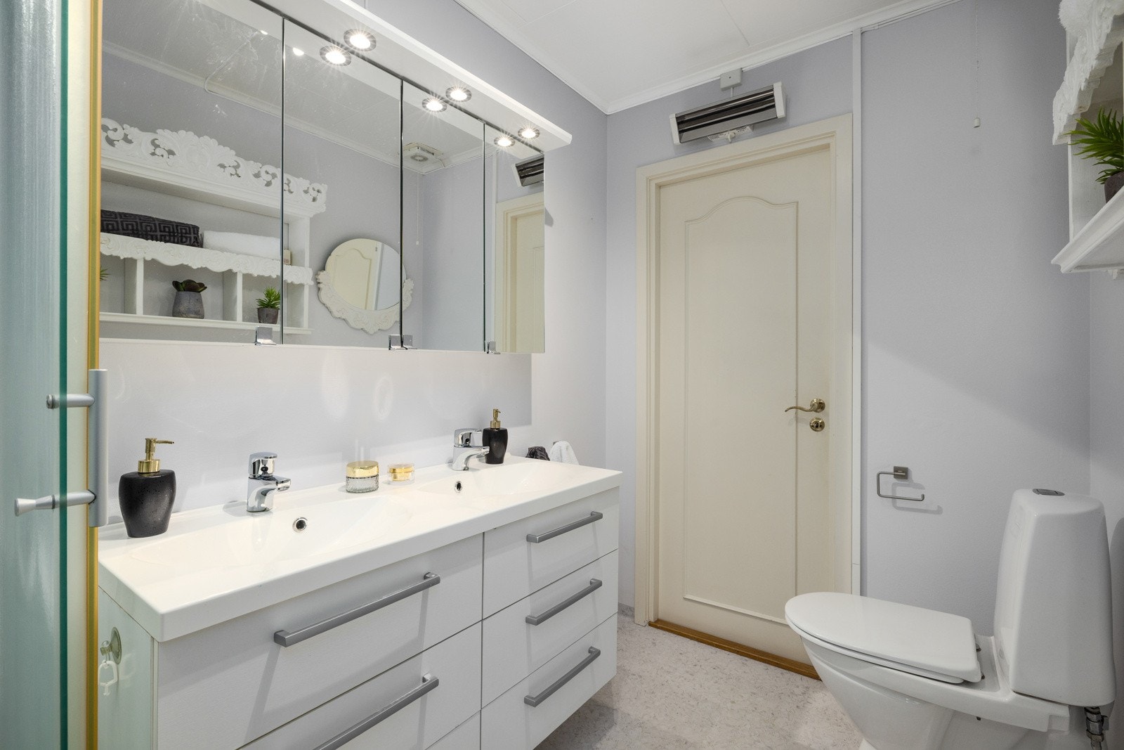 Badet er utstyrt med dobbel servant i underskap, overskap med speil og belysning, dusjkabinett og gulvmontert wc. Stråleovn. Mekanisk avtrekk Galleribilde