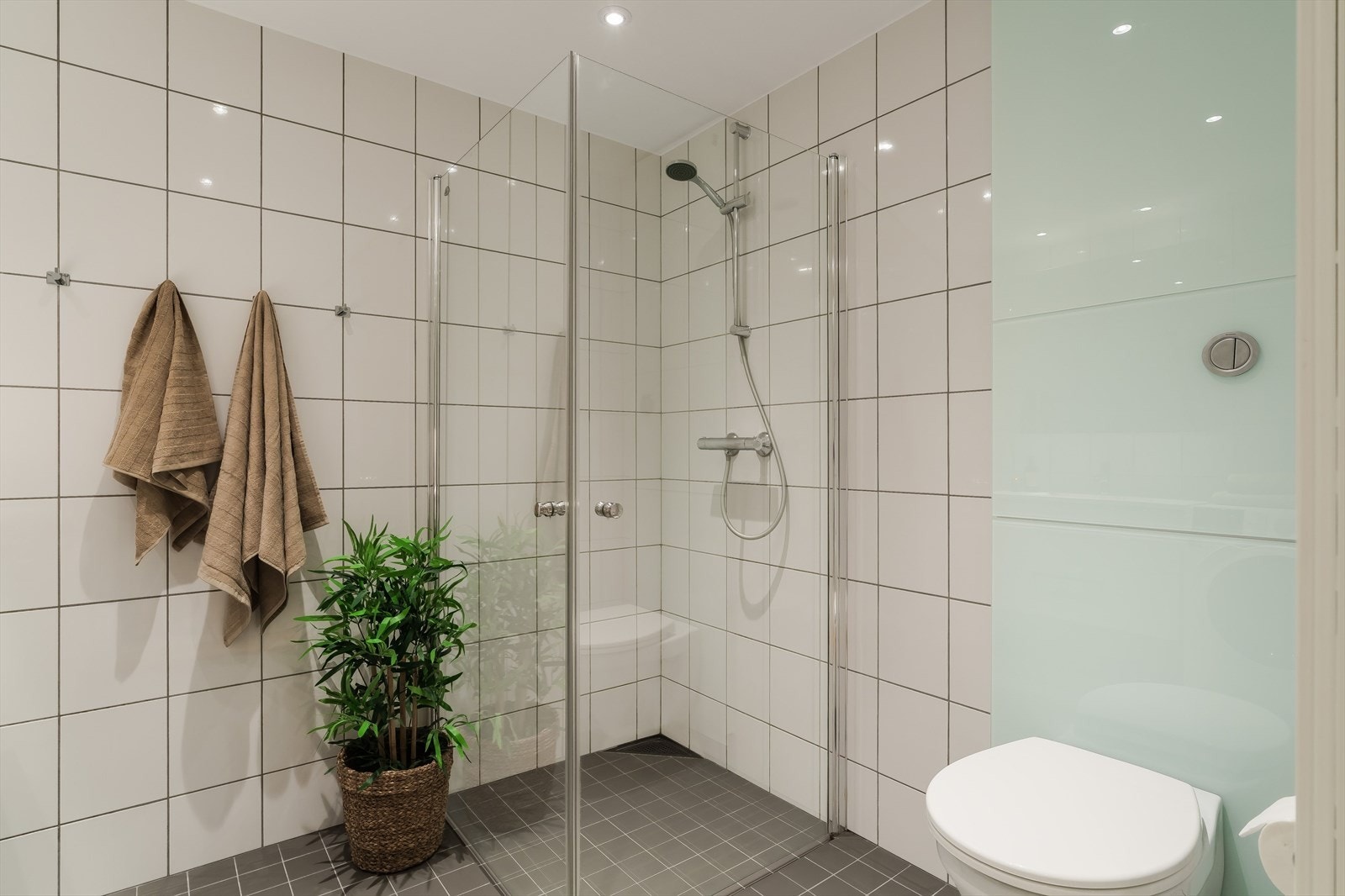 Rommet er innredet med servant med innredning, speil og dusjløsning med glassvegger. Det er vegghengt toalett og opplegg for vaskemaskin. Galleribilde