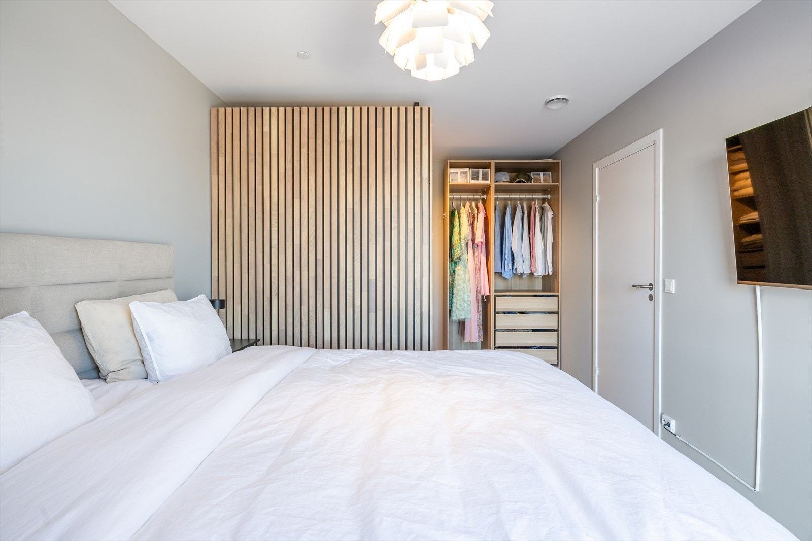 Garderobeløsning med trespiler, hyller og heng i ene enden av rommet. Galleribilde