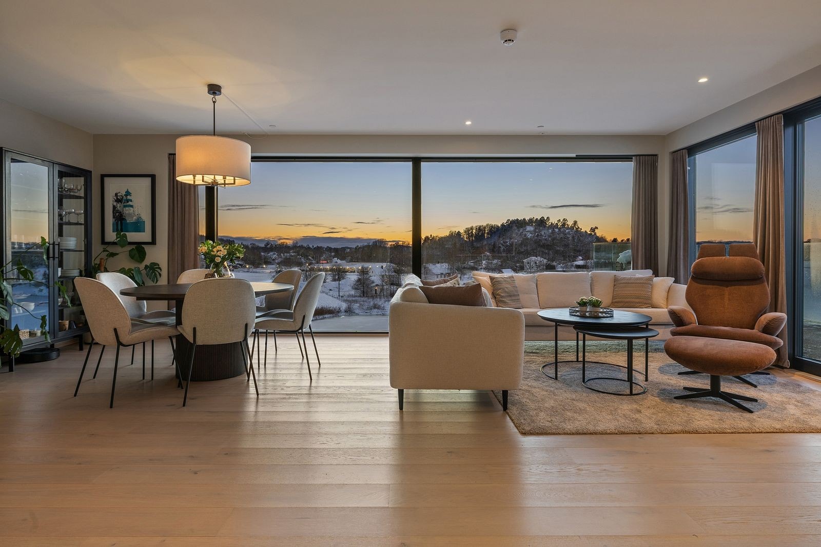 Romslig stue med åpen kjøkkenløsning. Store vinduer helt ned til gulvet for maksimal utsikt og innslipp av naturlig lys Galleribilde