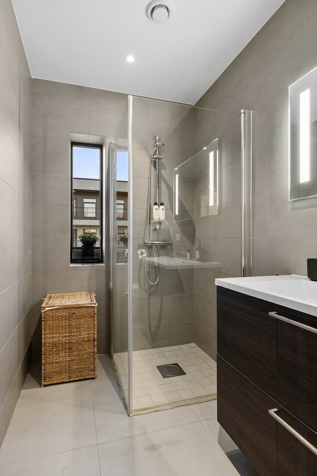 Badet er innredet med servant i baderomsmøbel, veggmontert toalett og dusjhjørne. Galleribilde