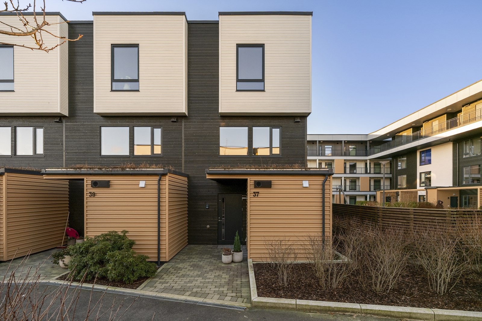 Inngangsparti er lagt med belegningsstein. Her kan en kopp kaffe og morgensolen nytes, frem til ca. 09:30 midtsommers. Boligen har også utvendig bod på denne siden. Galleribilde