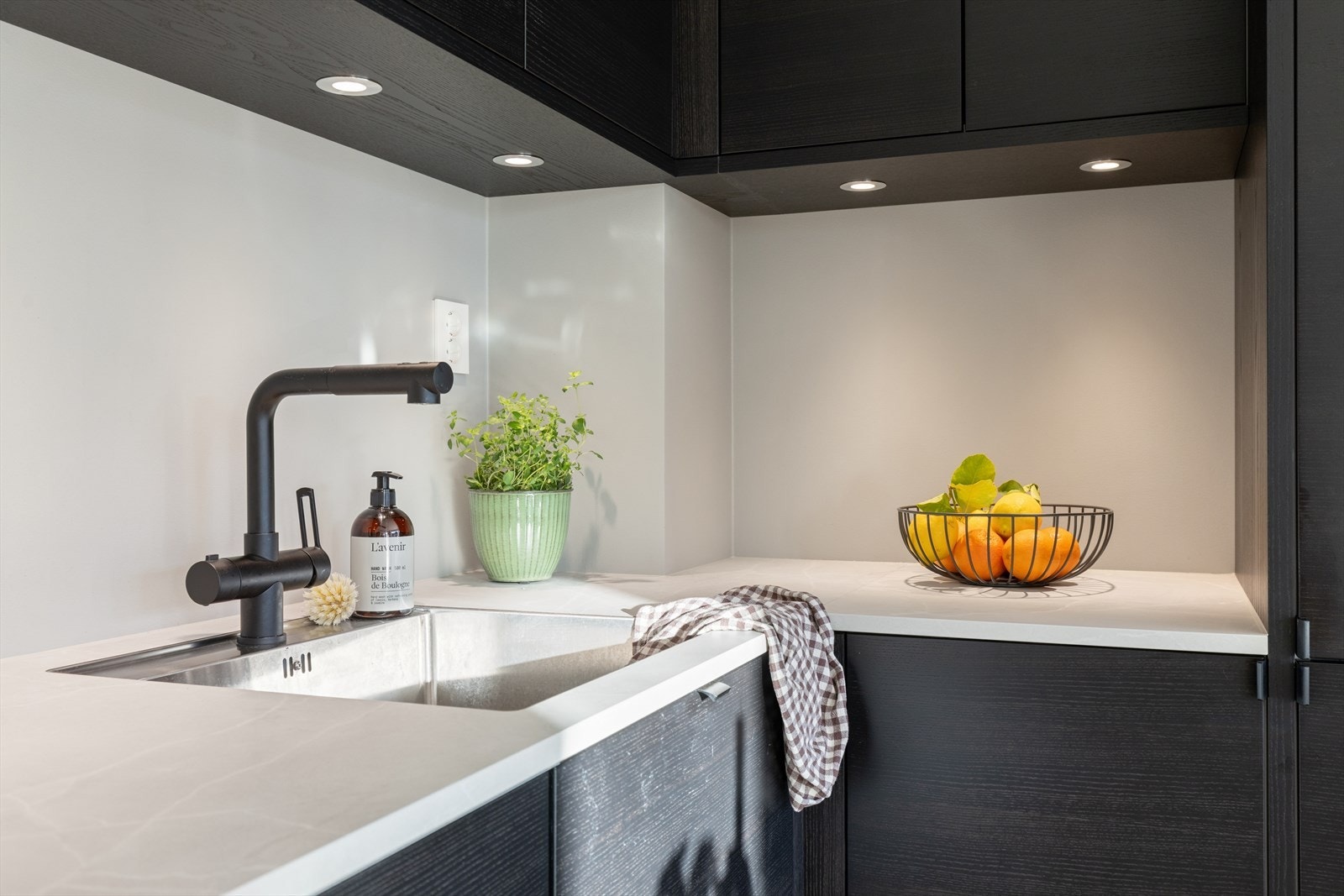 Detaljer som underlimt vask og sort armatur understreker den gjennomførte stilen. Galleribilde