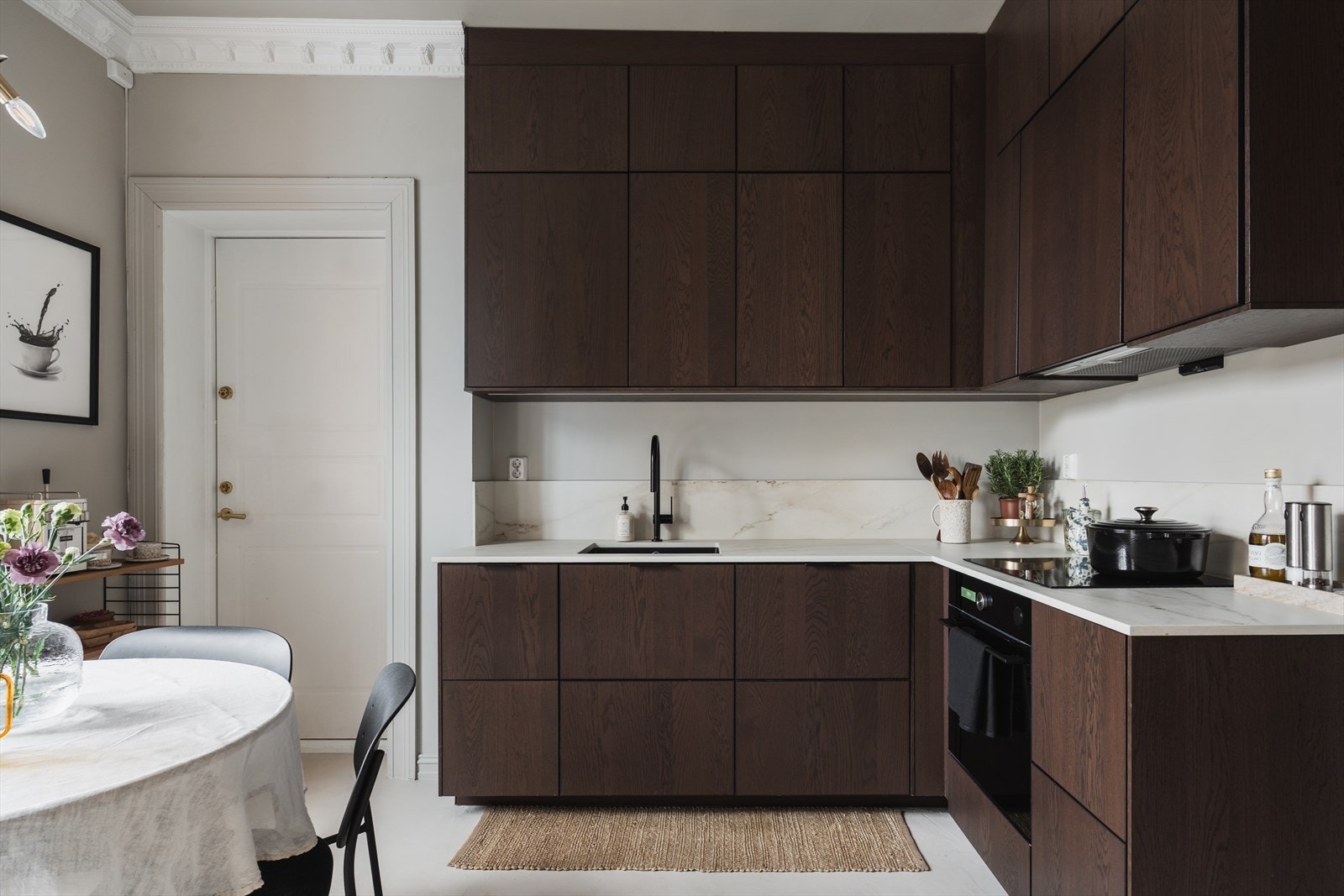 Tidløs kjøkkeninnredning fra 2022 med glatte fronter og benkeplate og backsplash i kompositt fra Nerostein med underlimt kum i kompositt. Det er integrert induksjonsplatetopp, stekeovn og oppvaskmaskin Galleribilde