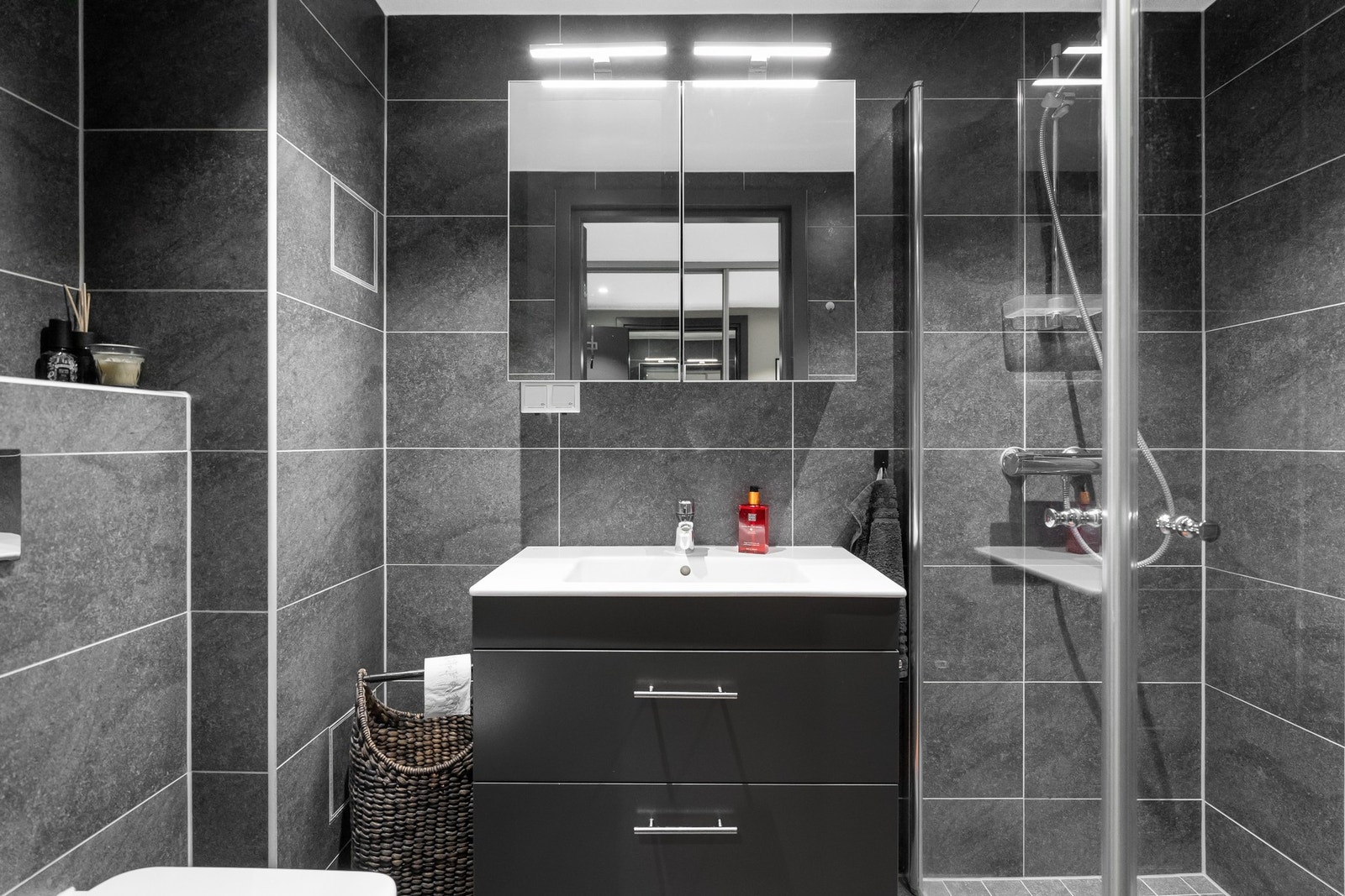 Begge badene i lik stil, fremstår moderne og delikat med helflisede vegger og flislagt gulv i tidløse fargetoner. Galleribilde