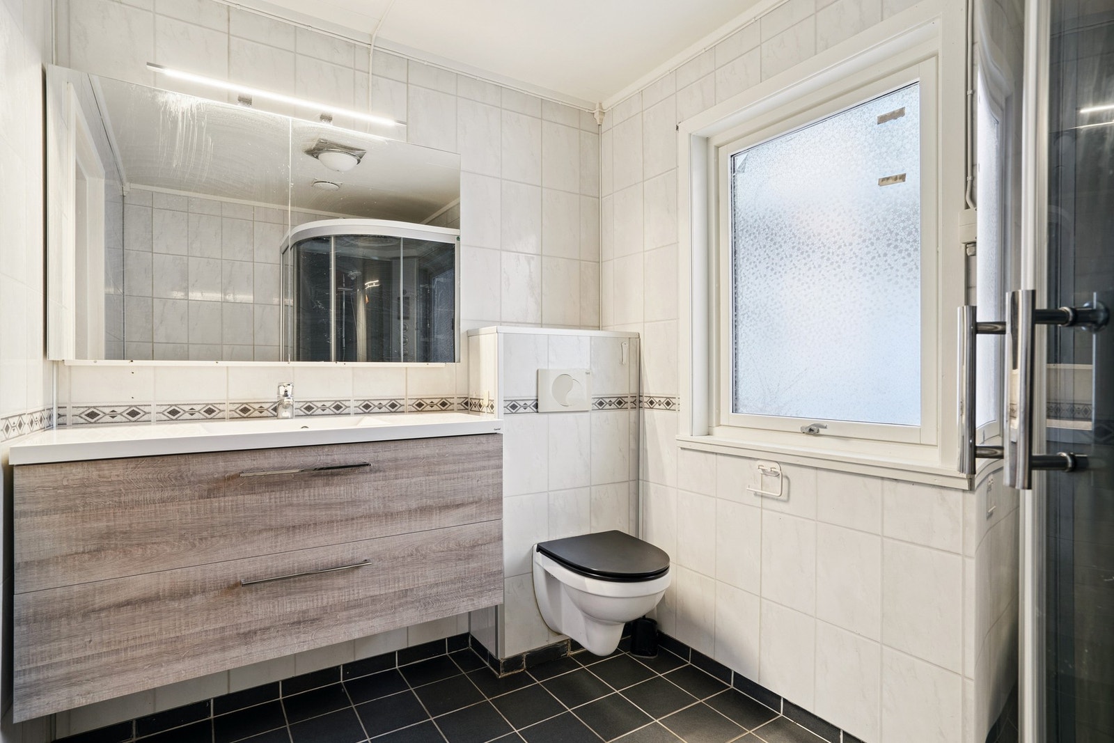 Bad i hovedetasjen har fliser på gulvet med elektriske varmekabler og våtromsplater på vegger. Galleribilde