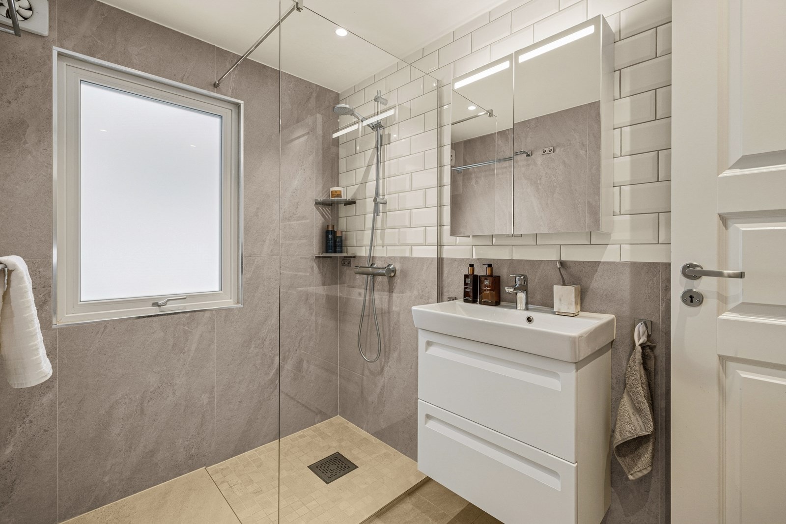 Rommet har flislagte vegger, malt himling og flislagt gulv med nedsenk i dusjsone. Det er elektriske varmekabler i gulv. Galleribilde