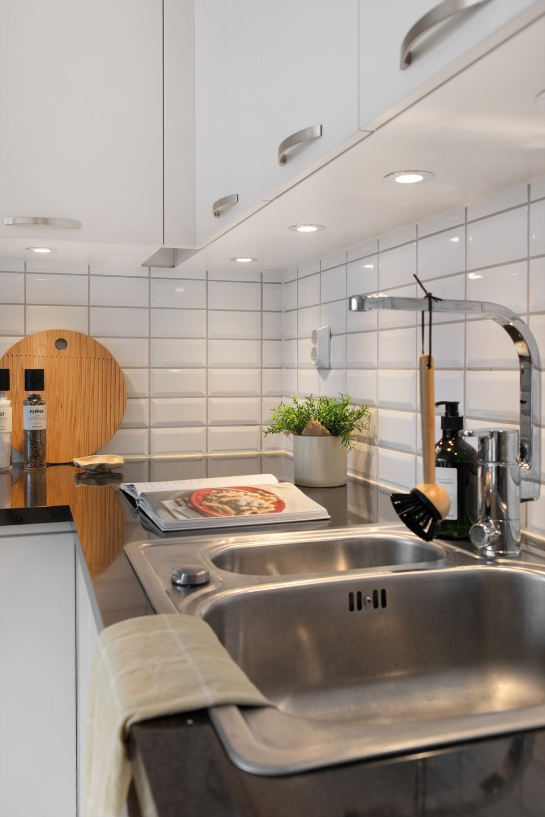 Kjøkkenet har god belysning og det er montert fliser på vegg mellom benkeplater og overskap. Galleribilde