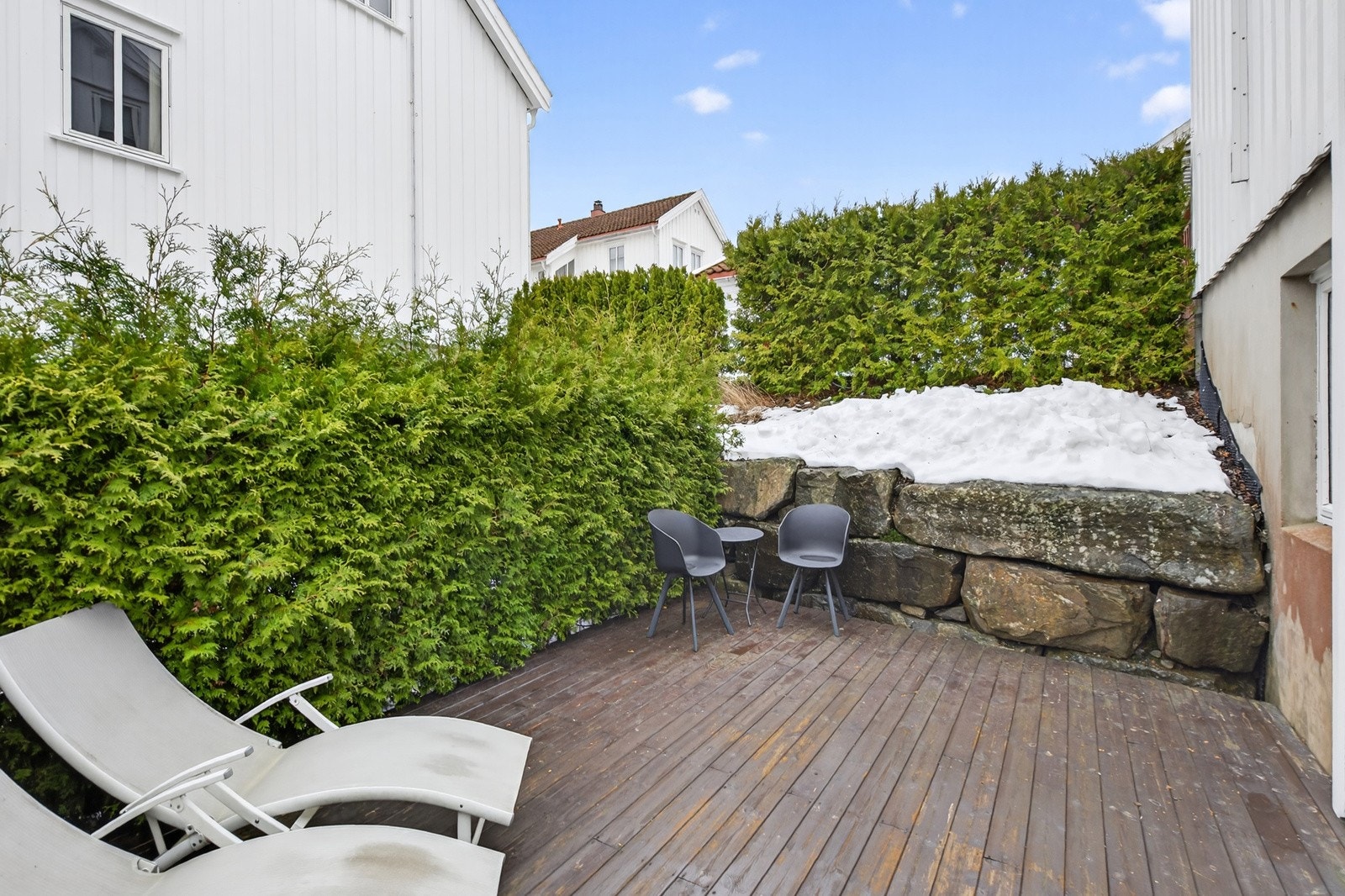 Pent opparbeidet uteplass som er innrammet av gjerder og hekker. Galleribilde