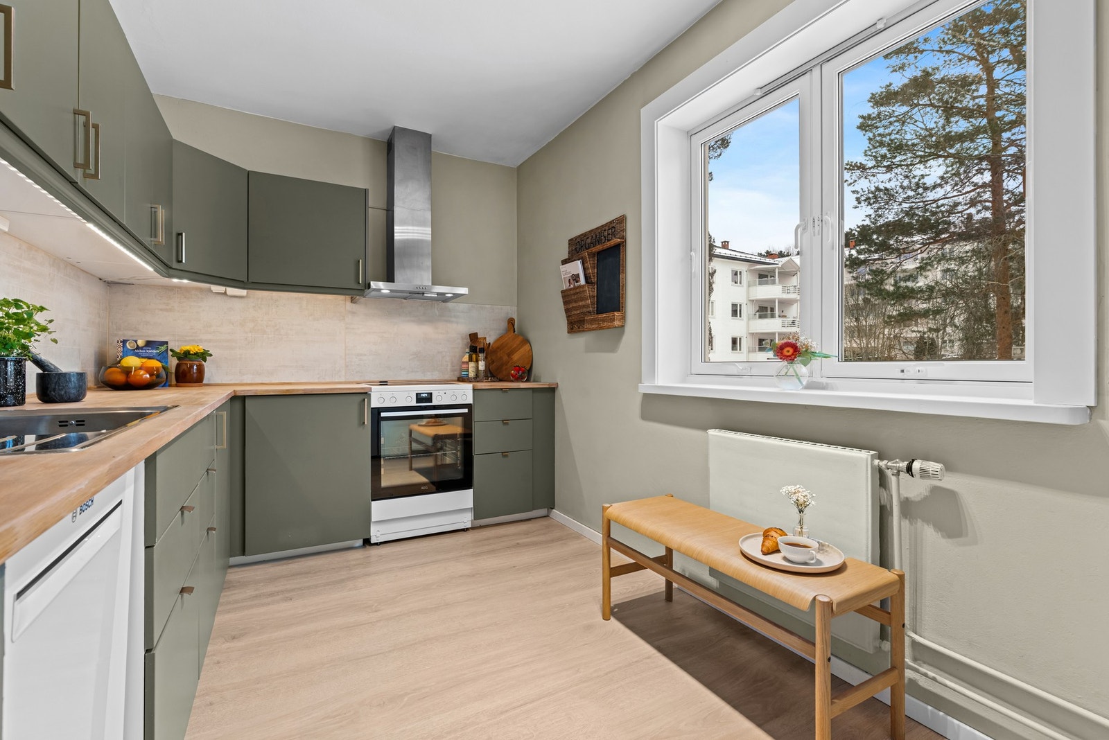 Innenfor entreen har leiligheten et romslig kjøkken. Et stort vindu bidrar med mye naturlig lys til matlagingen. Galleribilde
