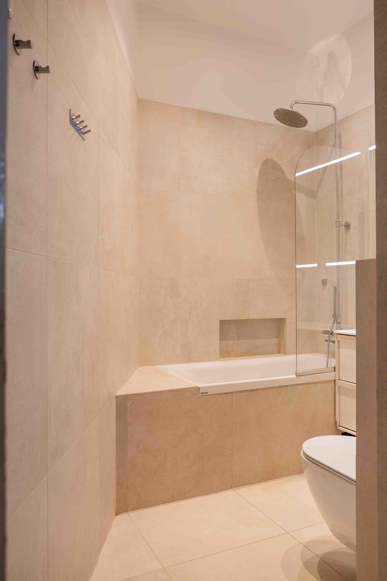 Badet er innredet med innmurt badekar, veggmontert toalett og servantskap Galleribilde