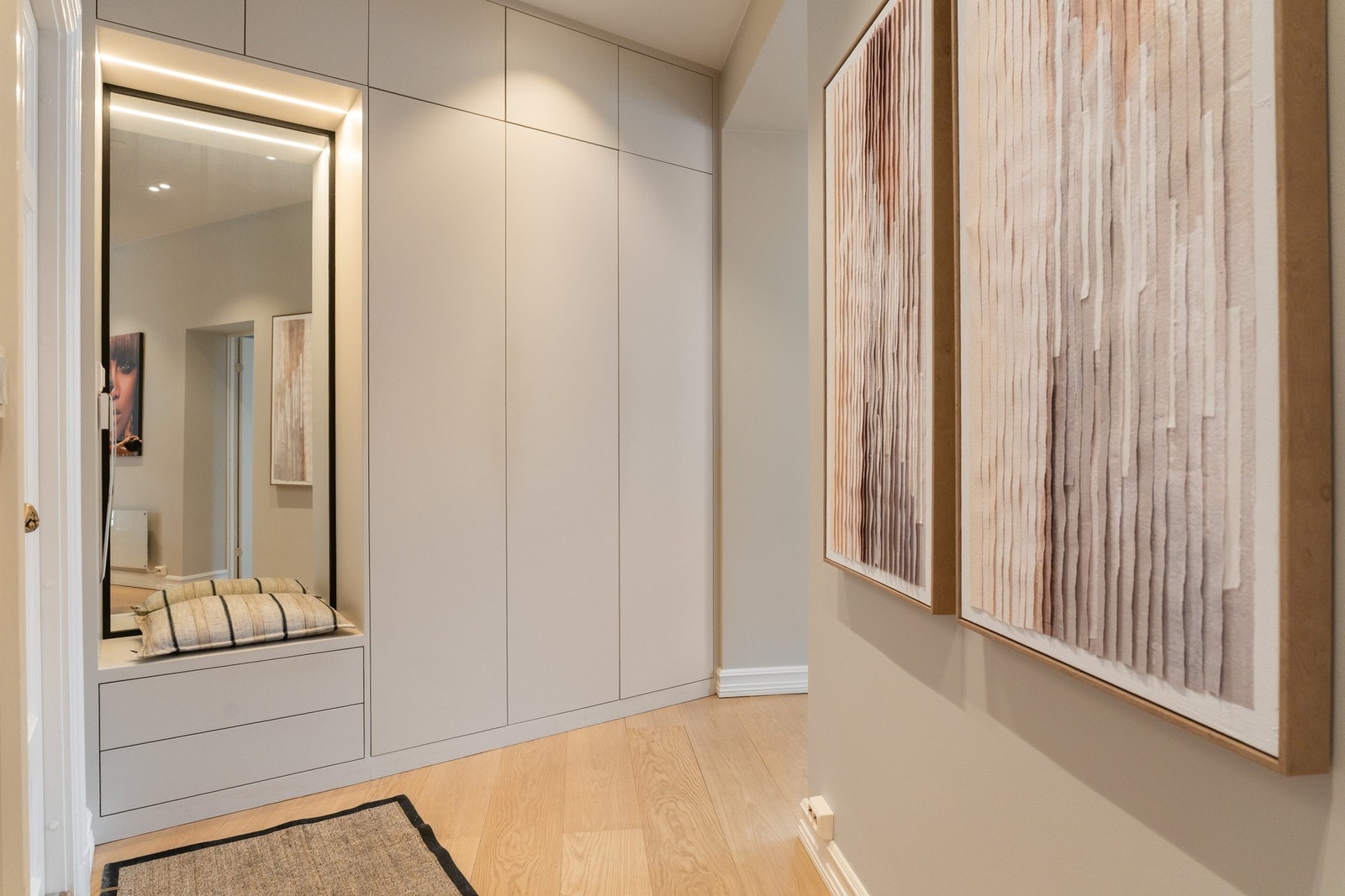 Flott plassbygd garderobeløsning med slette fronter, god skap og skuffeplass samt integrert sittebenk med oppbevaring. Videre er det speilfelt og innfelte downlights som gir god og behagelig belysning. Galleribilde