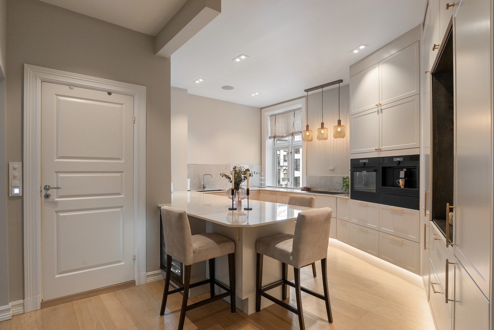 Stilrent og påkostet kjøkken fra Aubo (2024) med glatte fronter i tidløs utførelse og elegante messingfargede håndtak. Galleribilde