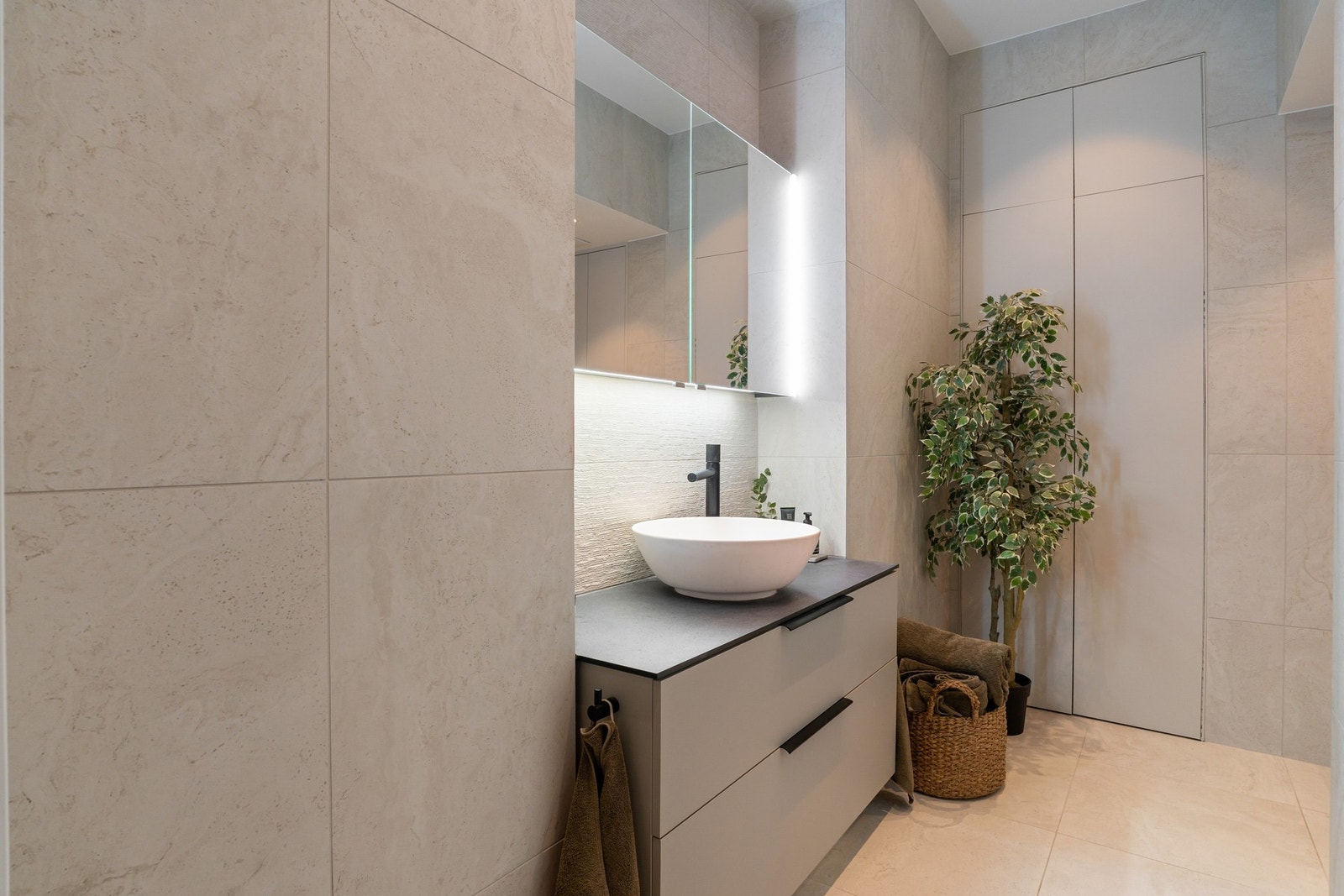 Delikat og påkostet bad fra 2023, utført i lyse og behagelige fliser som gir et tidløst og rolig uttrykk. Veggflater er belagt med fliser i 60 x 60 cm, kombinert med 30 x 60 cm fliser i integrerte nisjer med stemningsfull belysning. Galleribilde