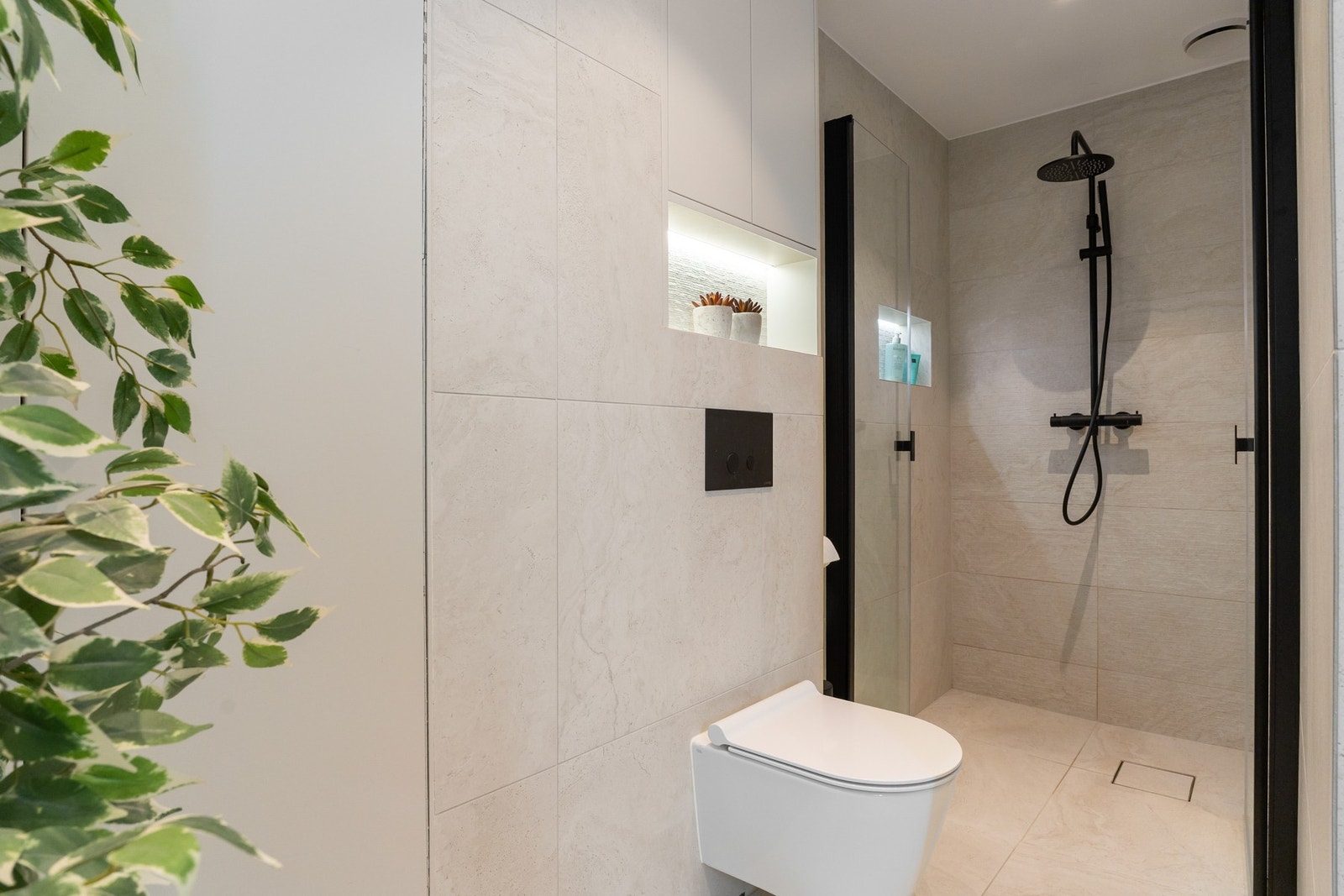 Dusjnisjen er romslig og avgrenset med fronter i herdet glass fra Strømberg, og har moderne dusjarmatur og dusjsystem fra Lavabo. Videre er badet utstyrt med GSI Kube X veggmontert toalett og stilrene sorte detaljer som gir en elegant kontrast. Galleribilde