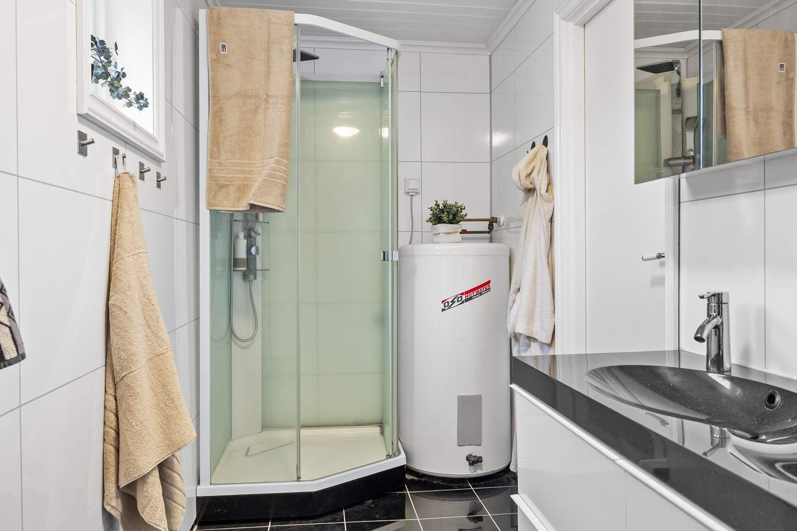 Innredningen består av dobbel nedfelt servant med god skapplass, toalett og dusjkabinett. I tillegg er det opplegg for vaskemaskin, noe som gjør rommet både arealeffektivt og praktisk kombinert som bad og vaskerom. Galleribilde