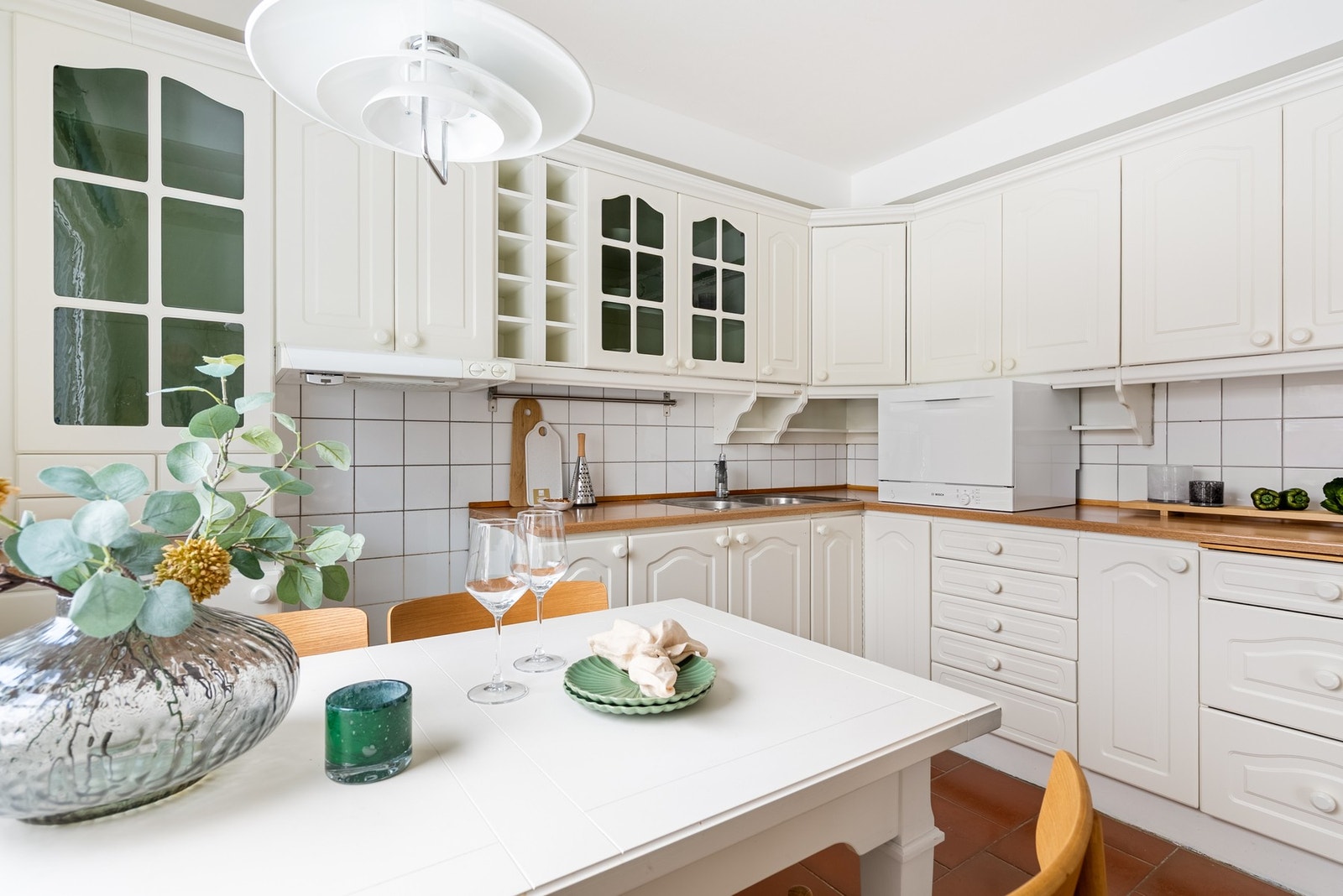 Fliser mellom kjøkkenbenk og overskap gjør rengjøringen enkel, mens god skapplass bidrar til å holde kjøkkenet ryddig og organisert Galleribilde